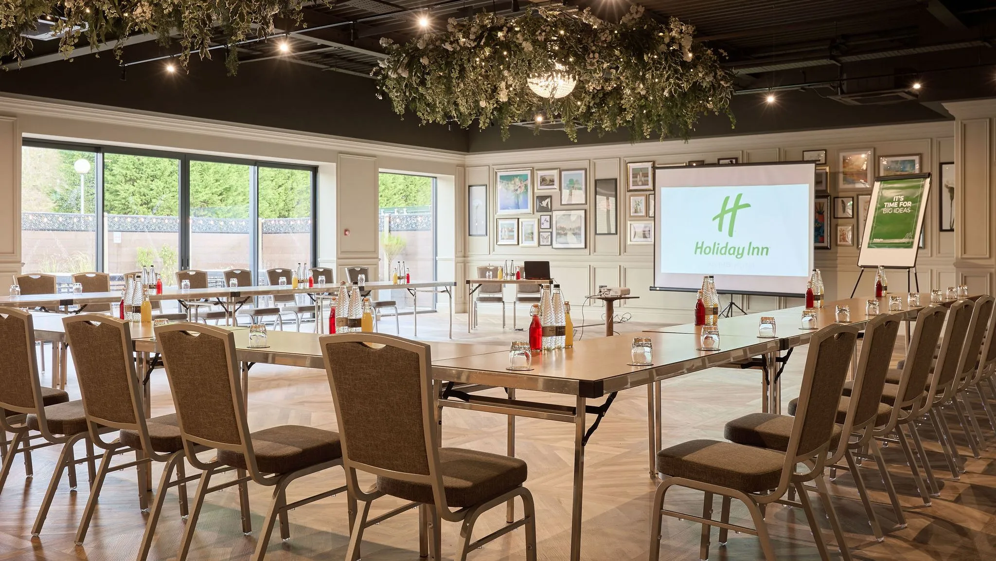 Meeting room at Holiday Inn with U-shaped conference layout, projector screen and floral ceiling décor