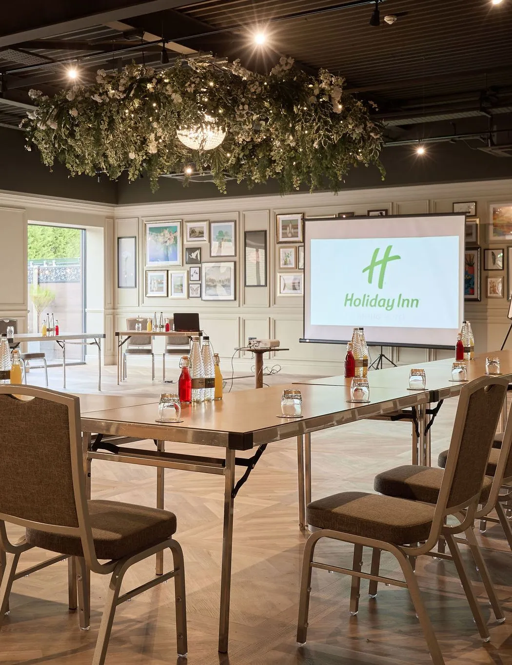 Meeting room at Holiday Inn with U-shaped conference layout, projector screen and floral ceiling décor