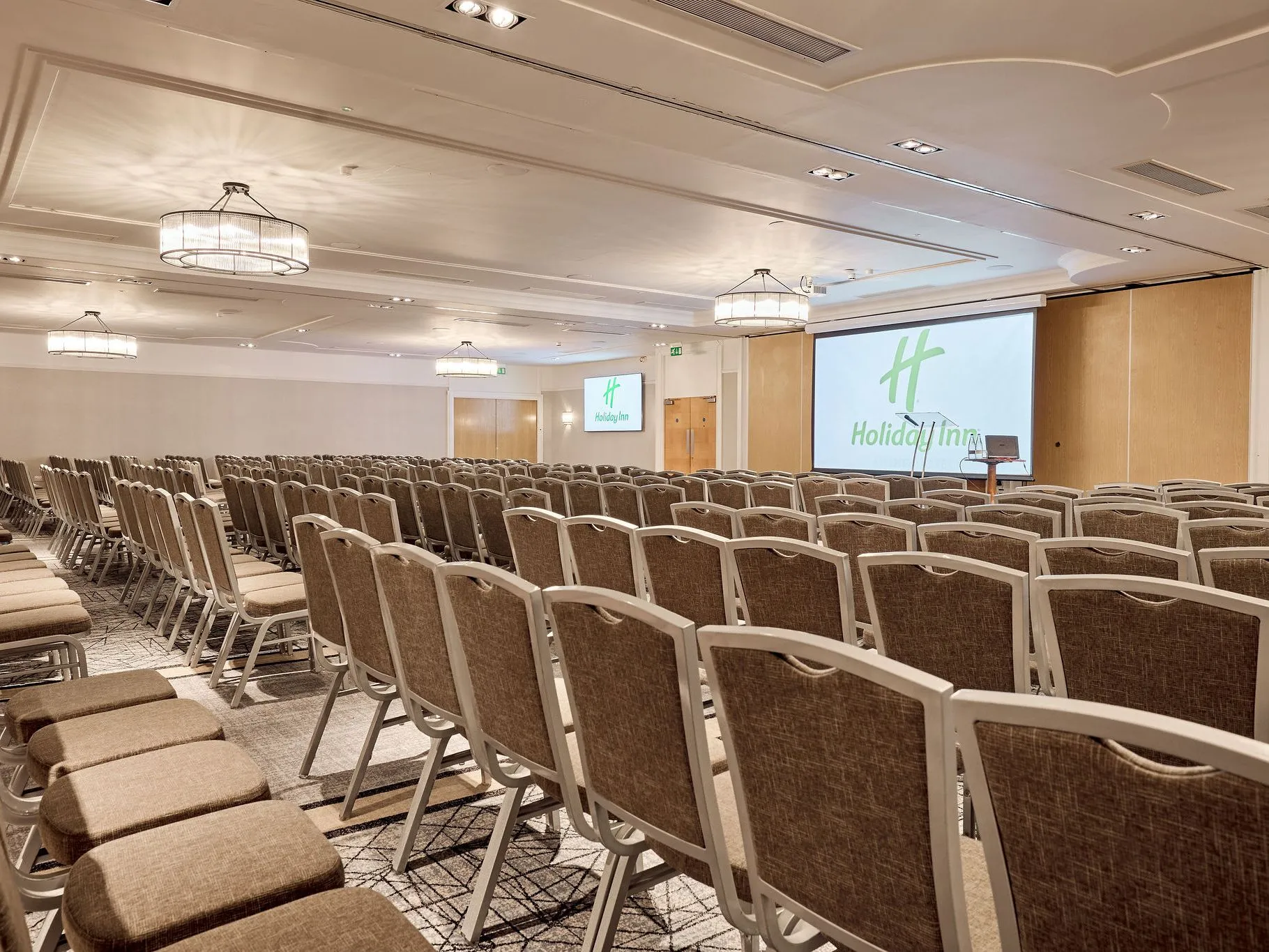 Conference room with rows of chairs facing a presentation screen at Holiday Inn