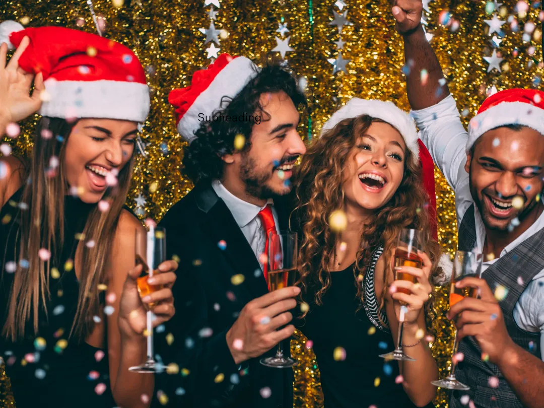 Four friends in Santa hats celebrating Christmas with drinks and falling confetti in front of a glittering gold backdrop.