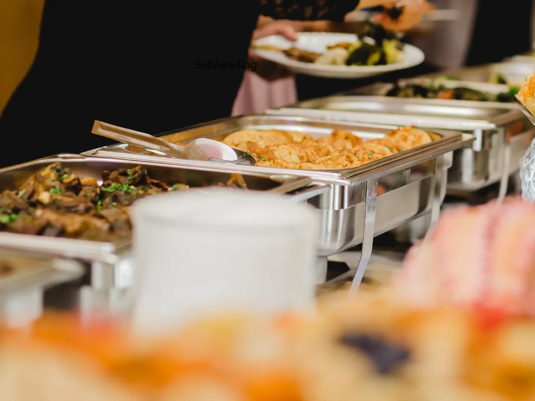 Guest serving food from a wedding buffet with hot dishes in silver trays