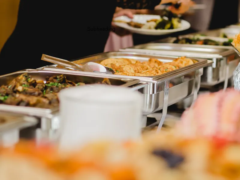 Guest serving food from a wedding buffet with hot dishes in silver trays