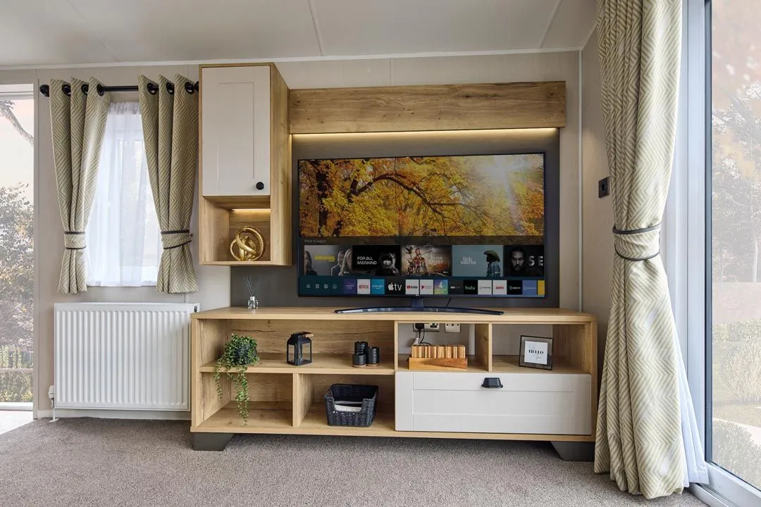 Modern living room TV unit with wood and cream cabinetry, shelves and patterned curtains