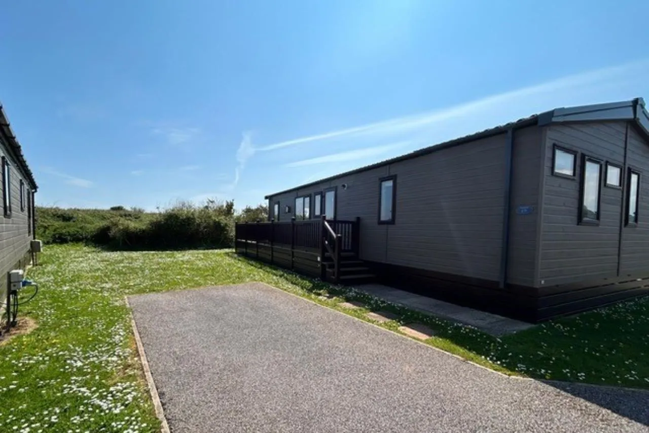 Static caravan with decking beside a paved driveway on a sunny day