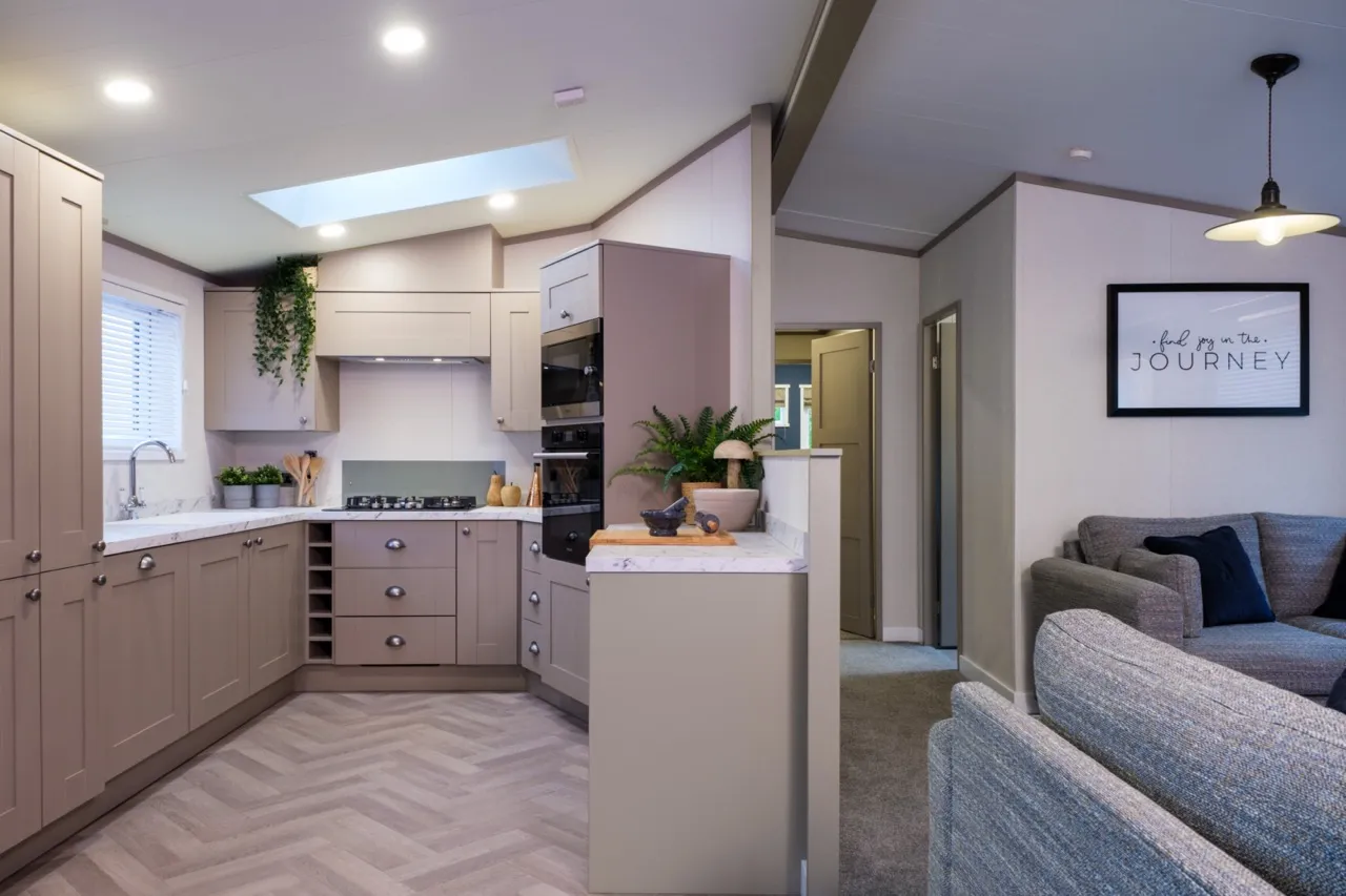 Modern open-plan kitchen and living area with grey cabinets, skylight and sofa
