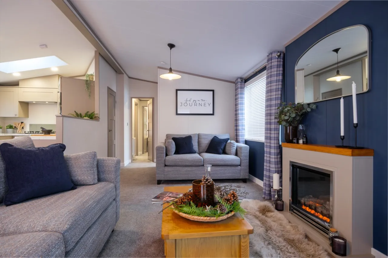 Modern living room with grey sofas, a wood coffee table and an electric fireplace on a blue feature wall