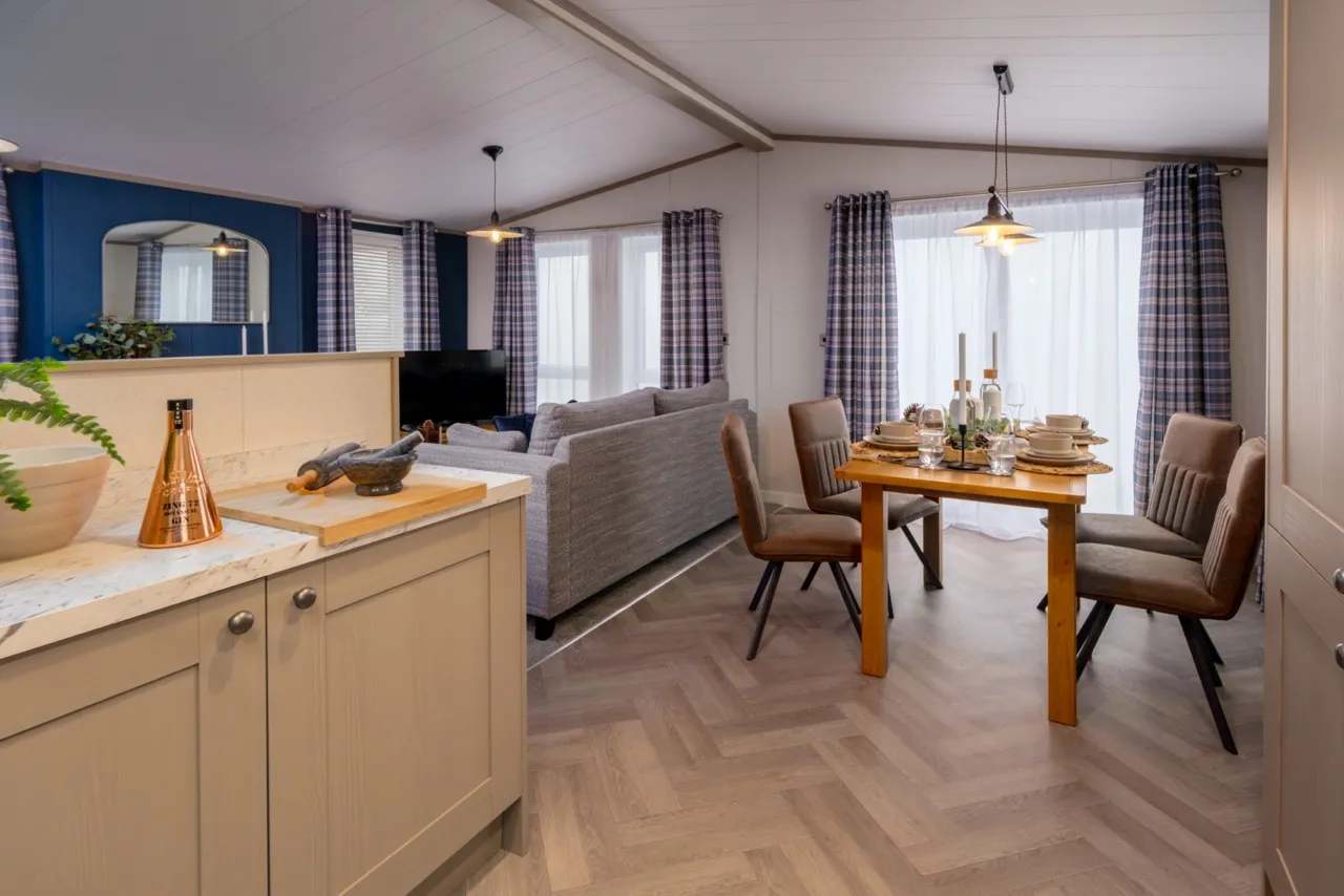Open-plan kitchen, dining and living area with grey sofa and set dining table