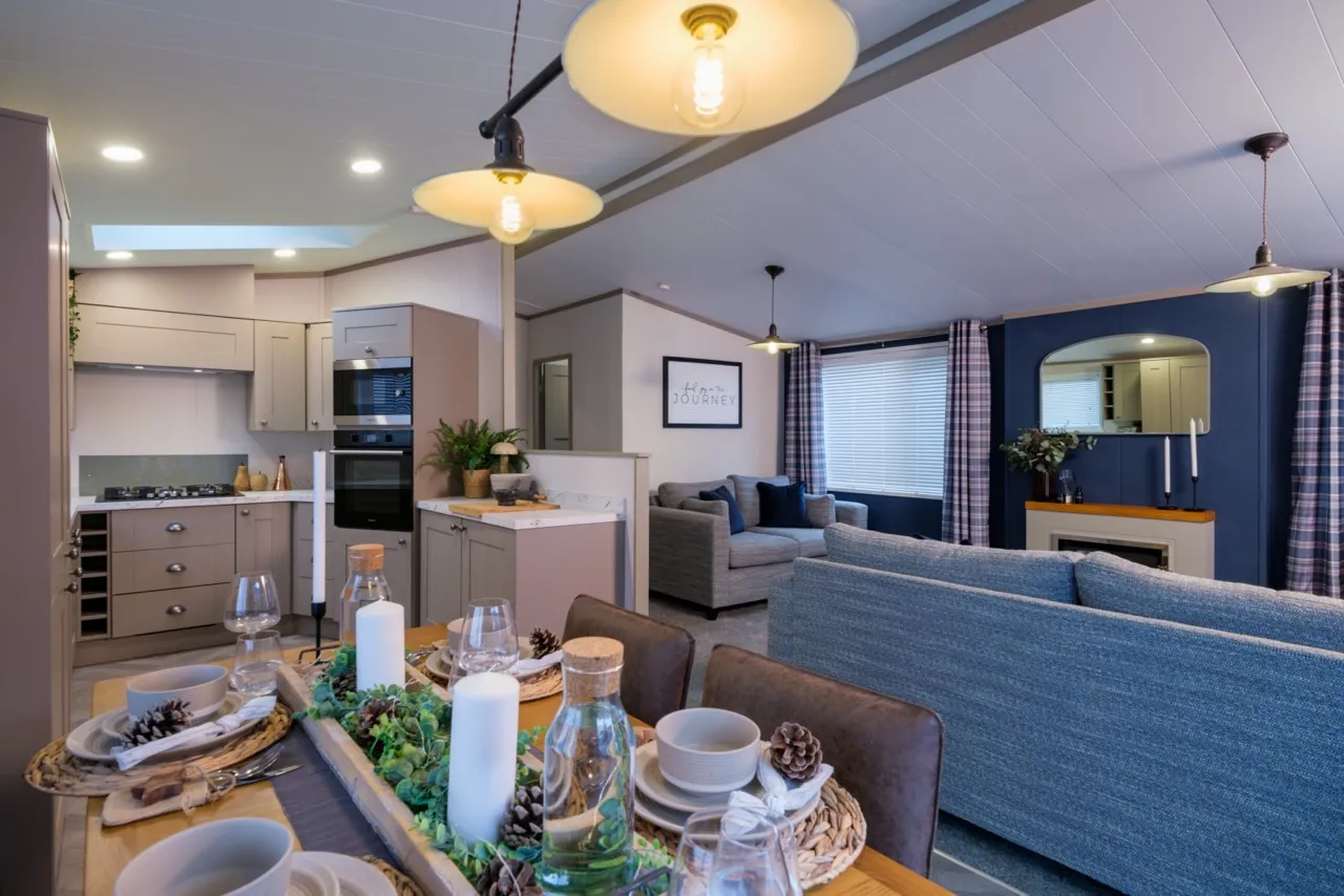Open-plan kitchen, dining and lounge area with grey cabinetry, set dining table and blue accent wall