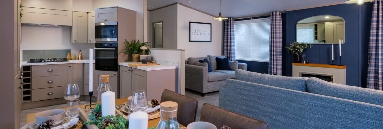 Open-plan kitchen, dining and lounge area with grey cabinetry, set dining table and blue accent wall