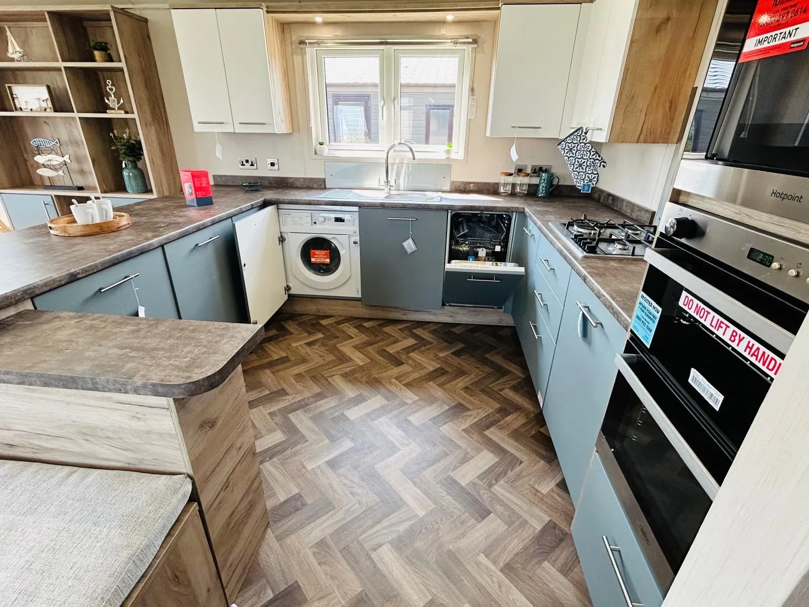 Modern U-shaped kitchen with blue-grey cabinets, white cupboards and herringbone floor