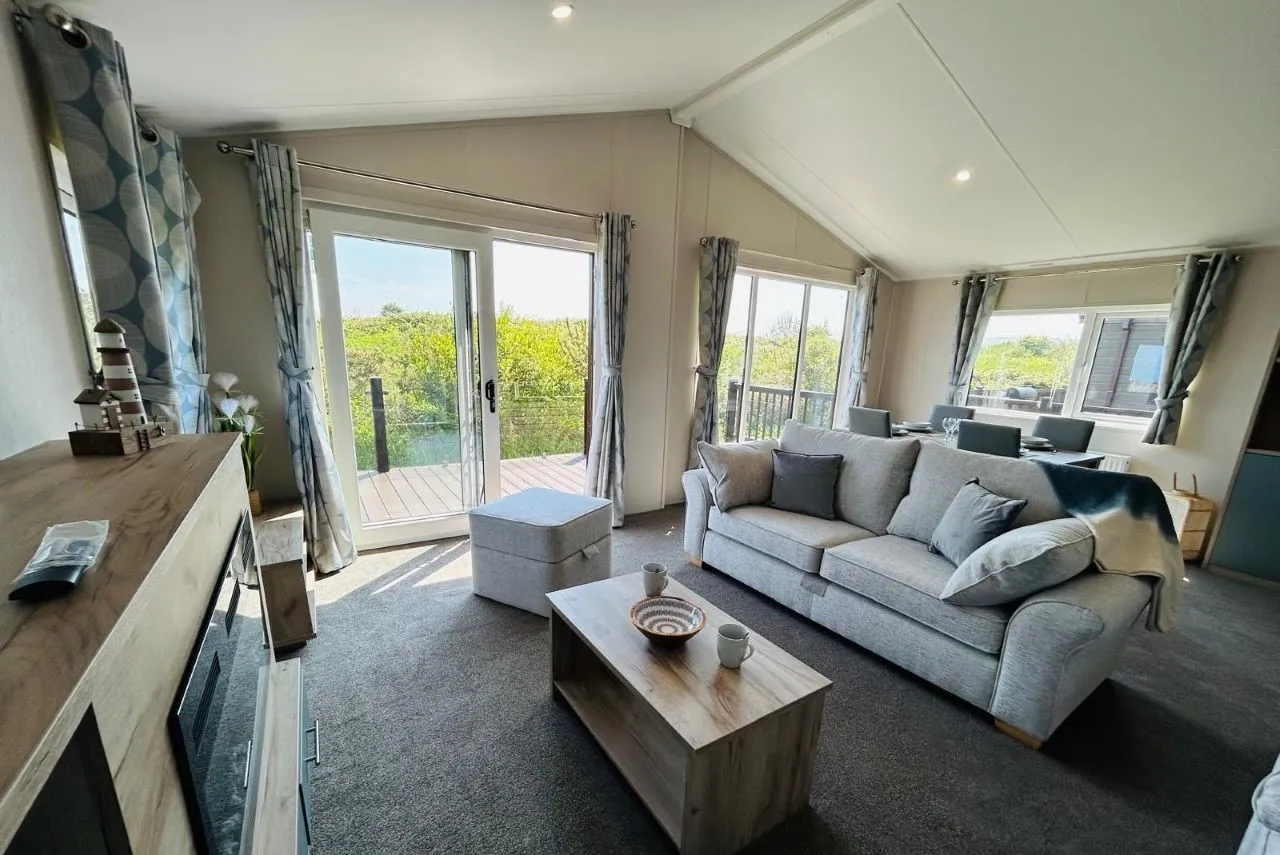 Modern living room with grey sofa, coffee table and large patio doors opening onto a deck