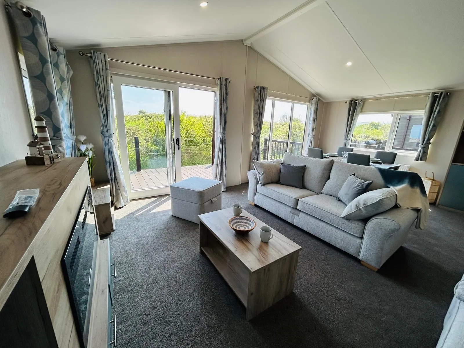 Bright modern living room with grey sofa, wooden coffee table and French doors to a balcony