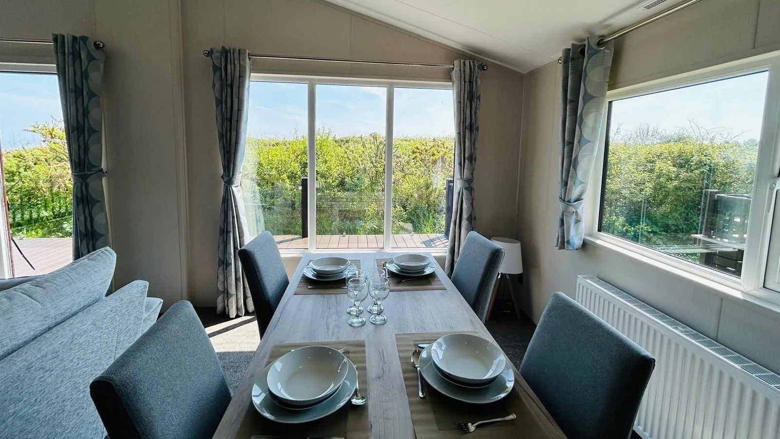 Dining table set for four beside large windows in a modern holiday lodge