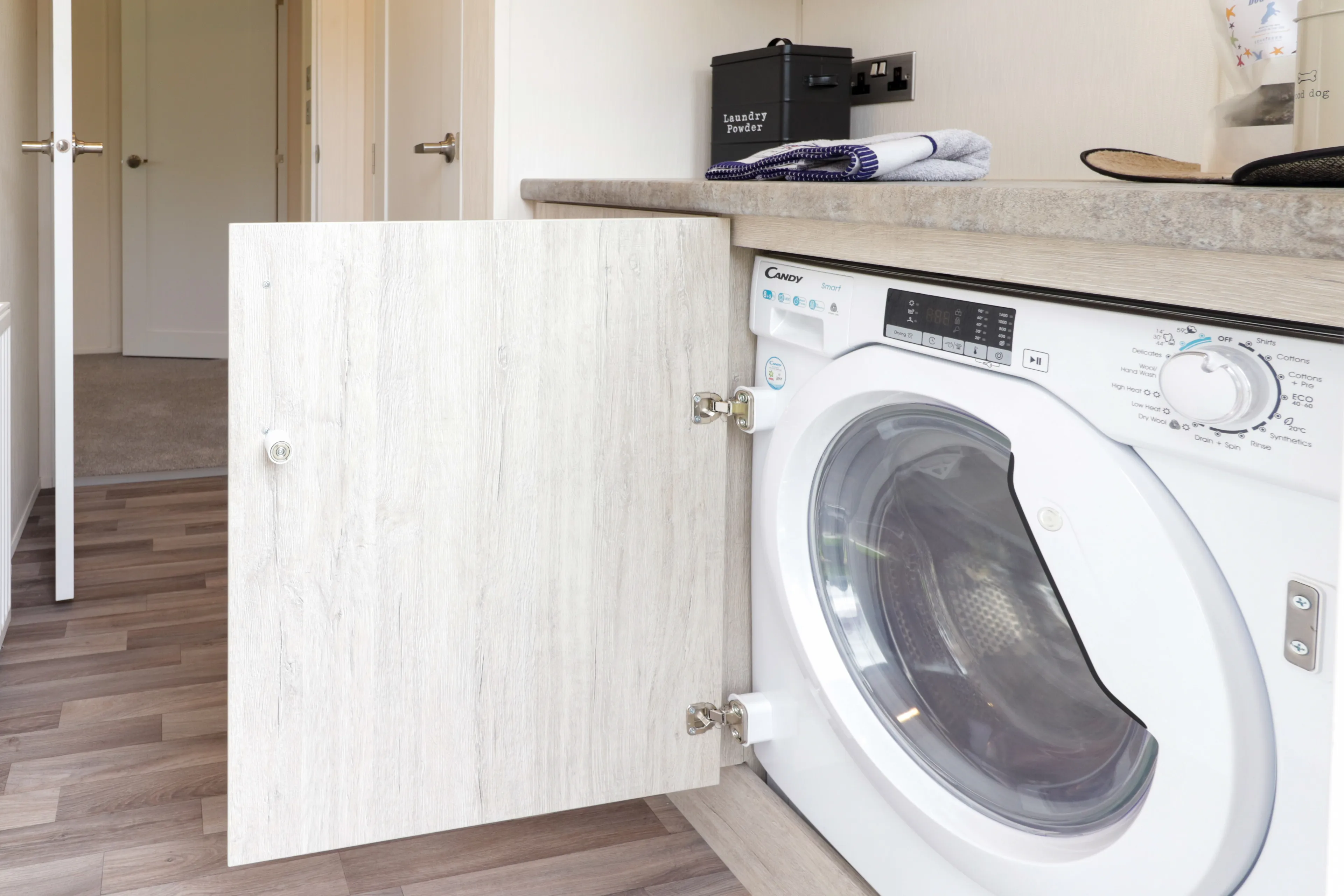 Built-in front-loading washing machine beneath a countertop with cabinet door open