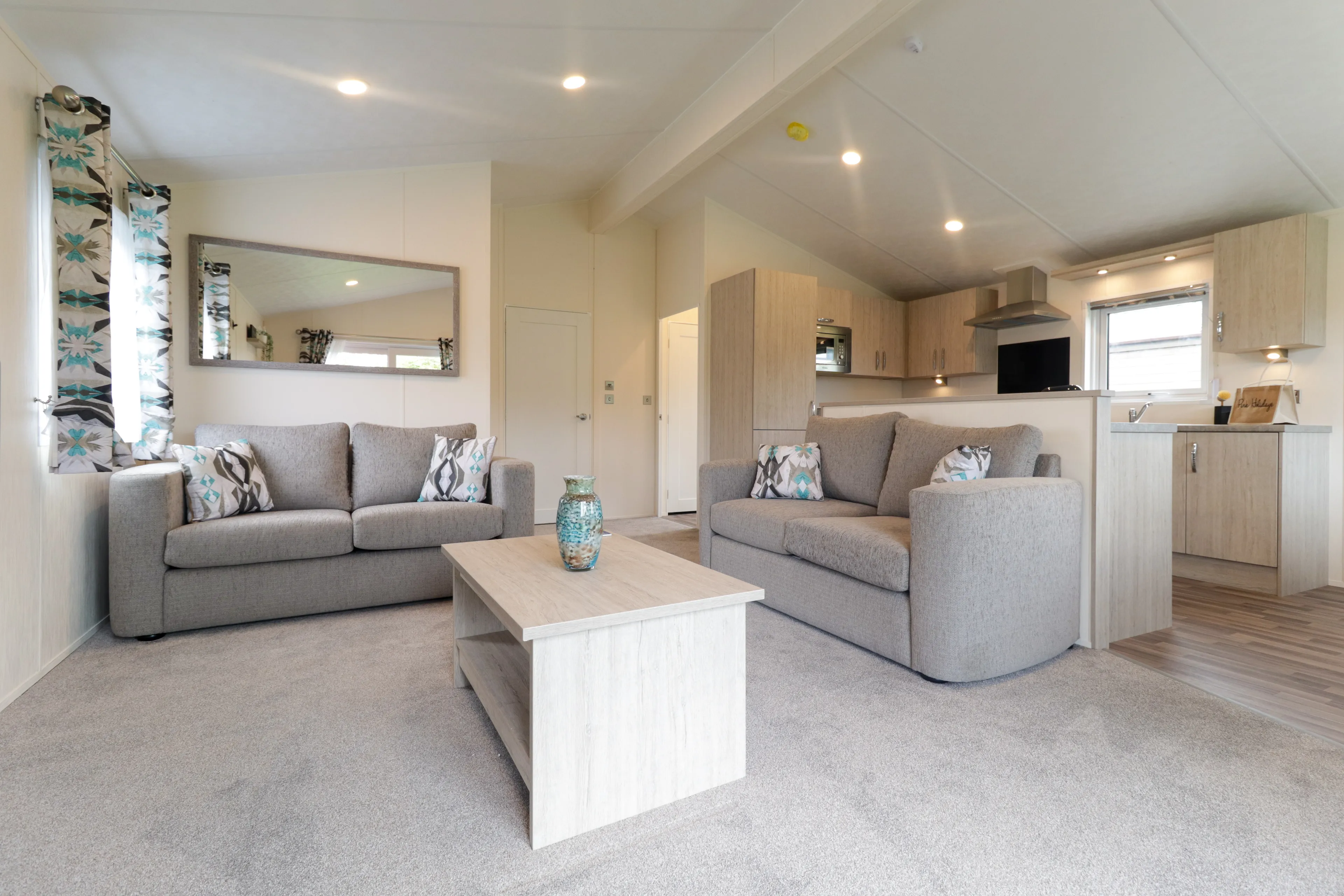 Modern open-plan living room and kitchen with two grey sofas and a light wood coffee table