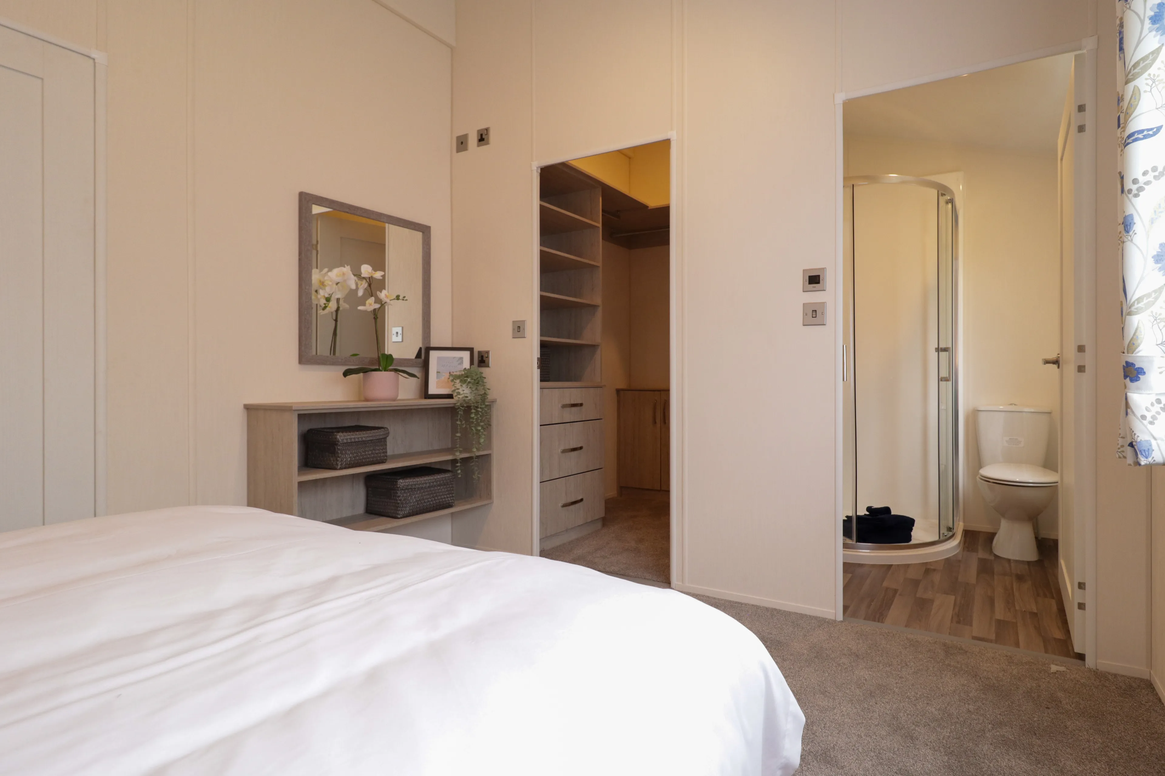Bright bedroom with bedside unit, mirror, walk-in wardrobe and en-suite shower room
