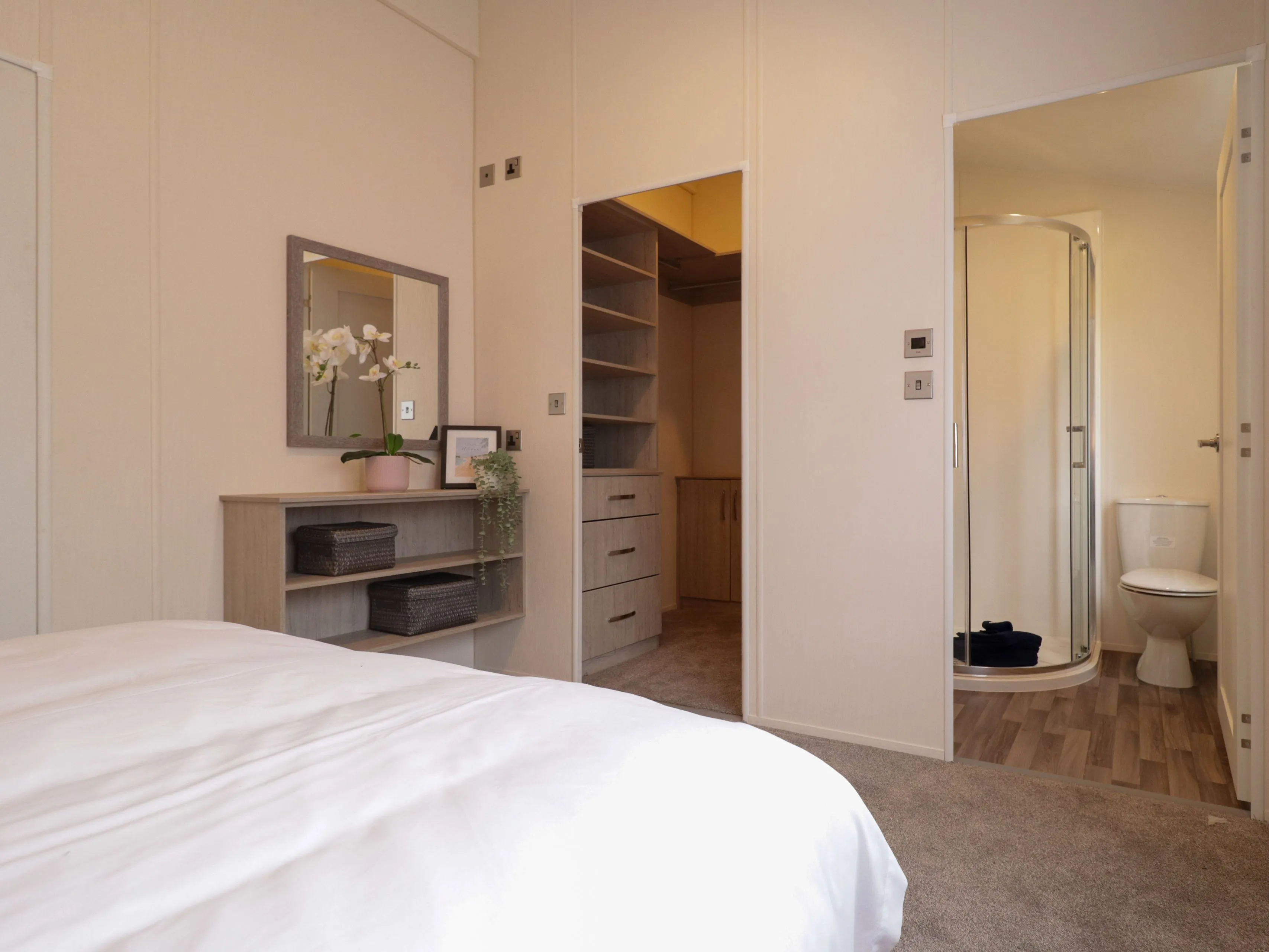 Bright bedroom with bedside unit, mirror, walk-in wardrobe and en-suite shower room