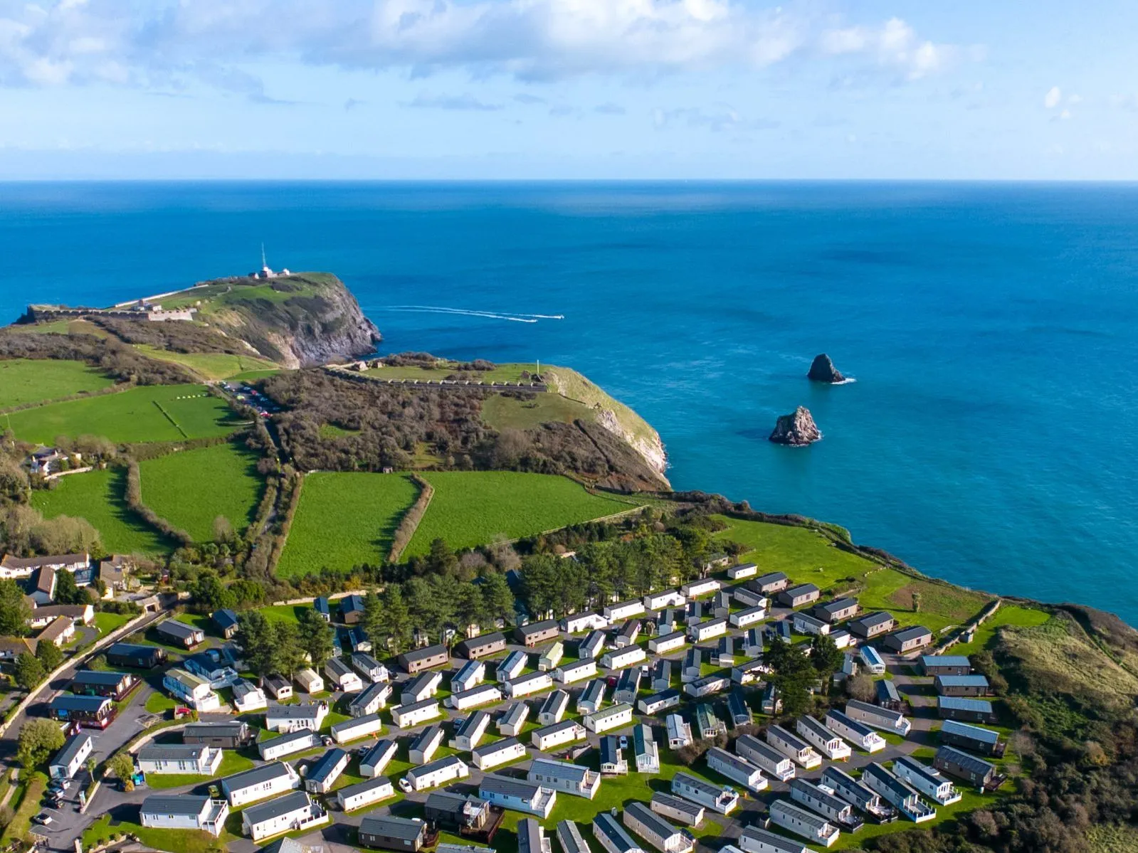 Drone view of Landscove holiday park on a coastal headland with green fields and blue sea