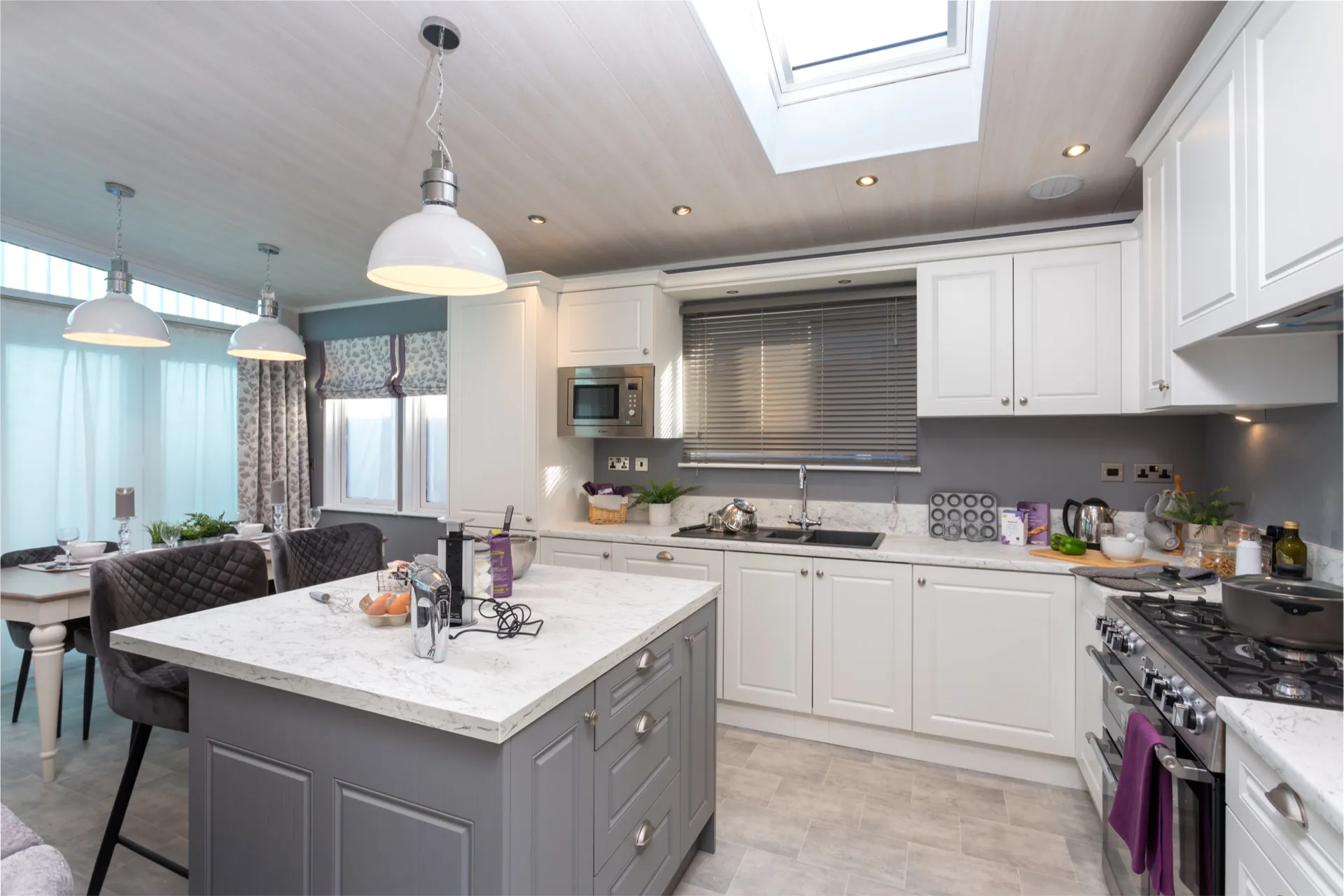 Modern kitchen with white cabinets, grey island and pendant lights under a skylight