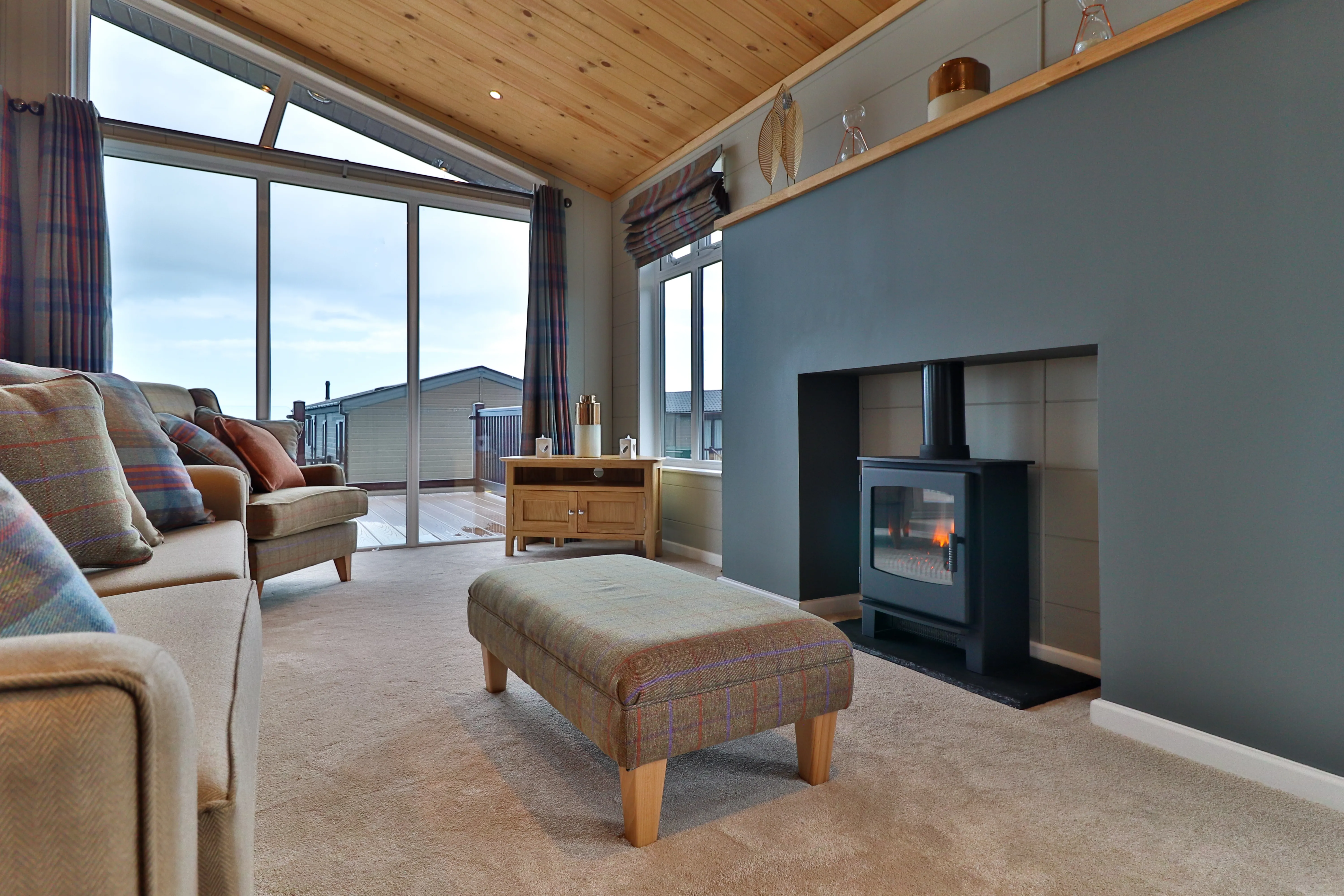 Cosy living room with wood-burning stove, large windows and sofa seating