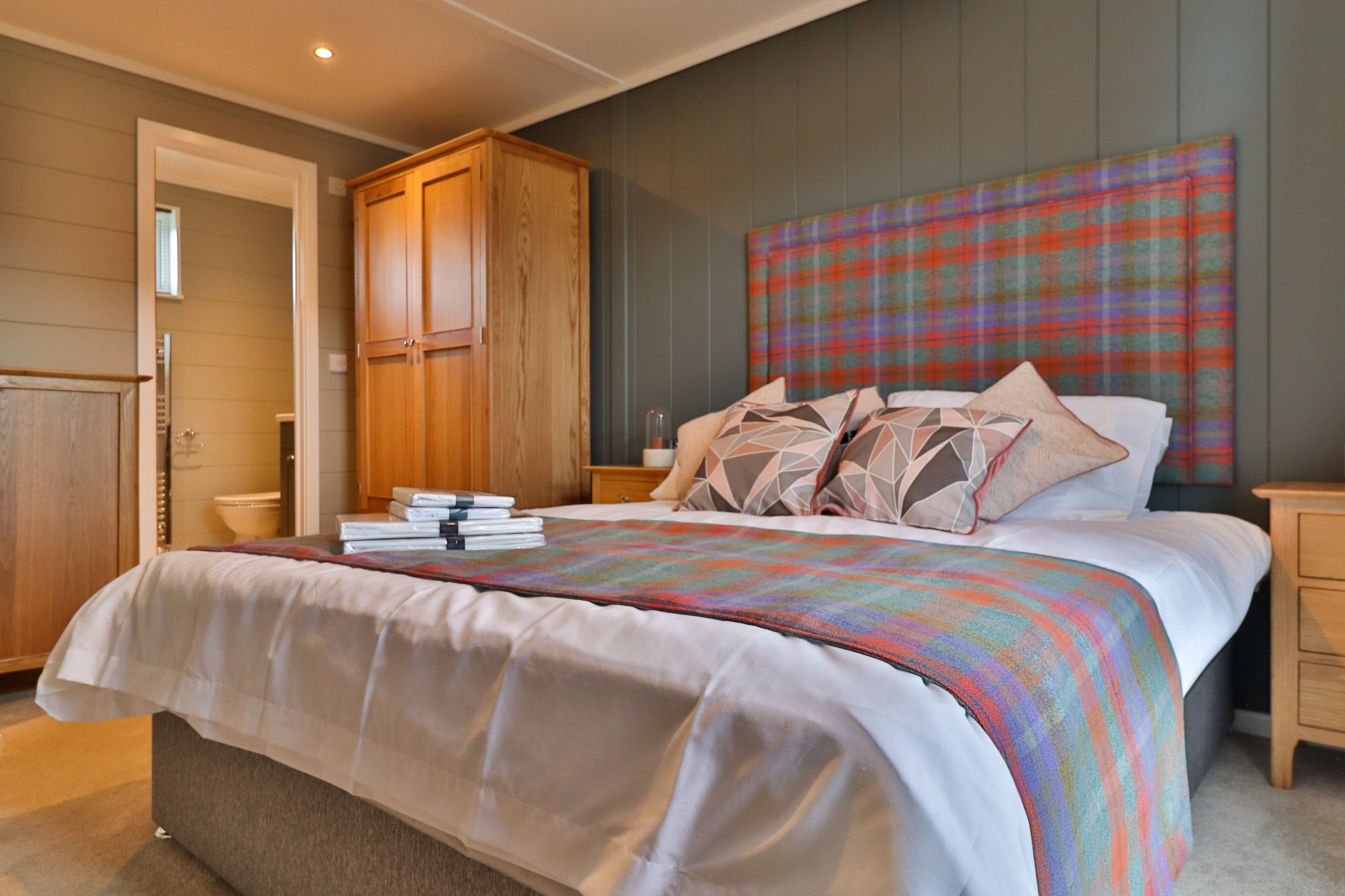 Cosy bedroom with tartan headboard, double bed and wooden wardrobe