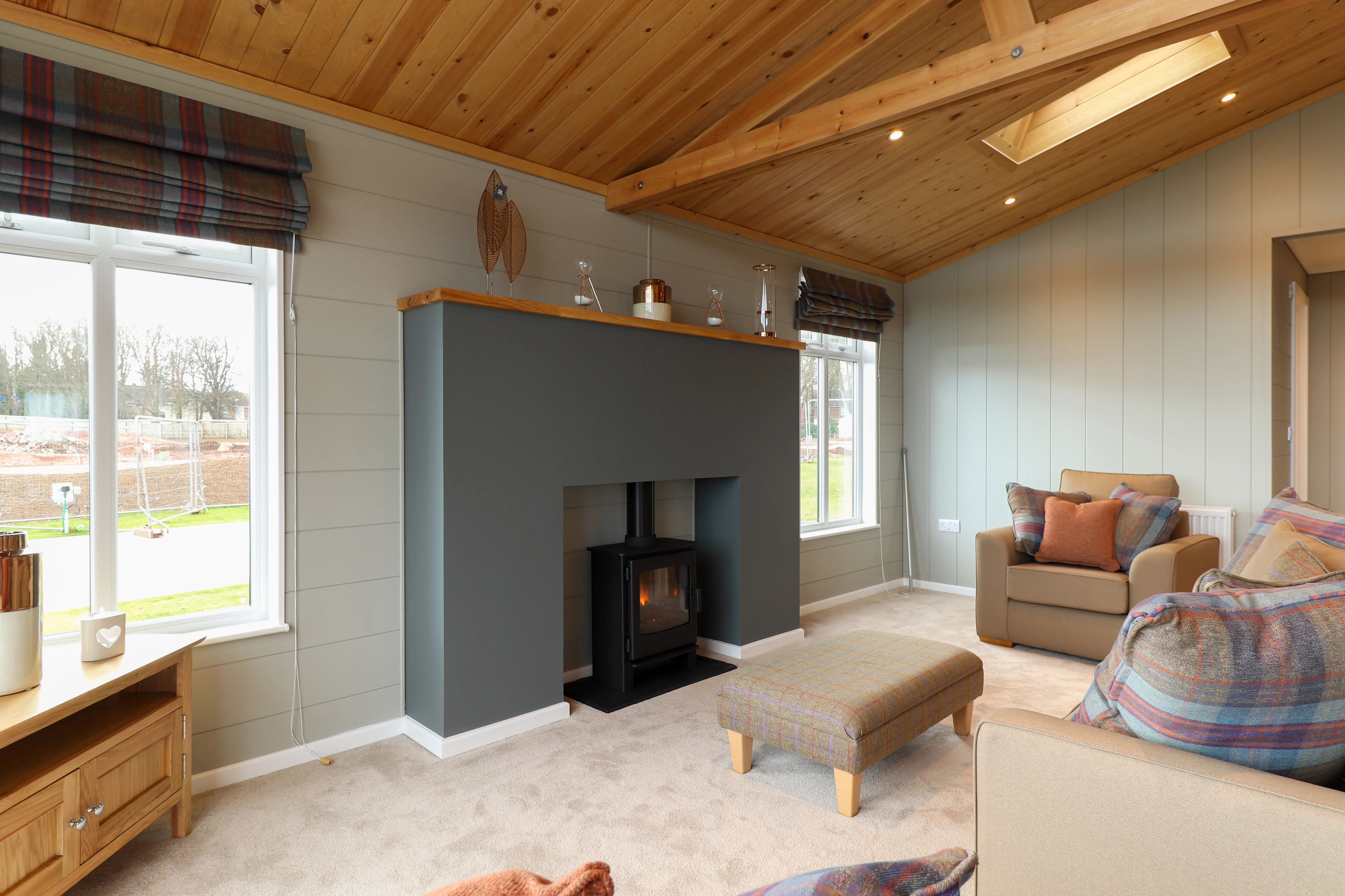 Cosy living room with wood-panelled ceiling, skylight and log-burning stove
