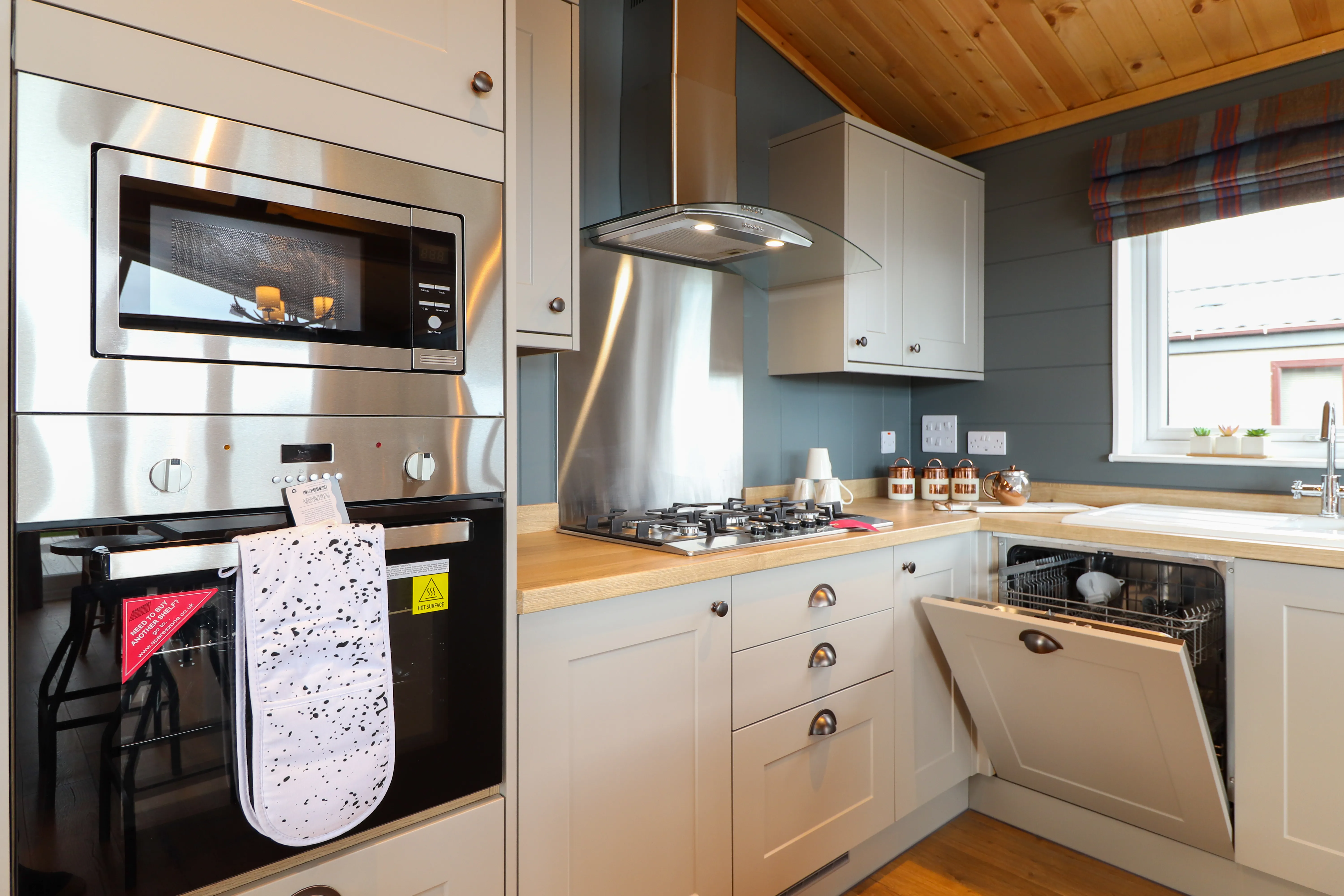 Modern kitchen with built-in oven and microwave, gas hob, and open dishwasher