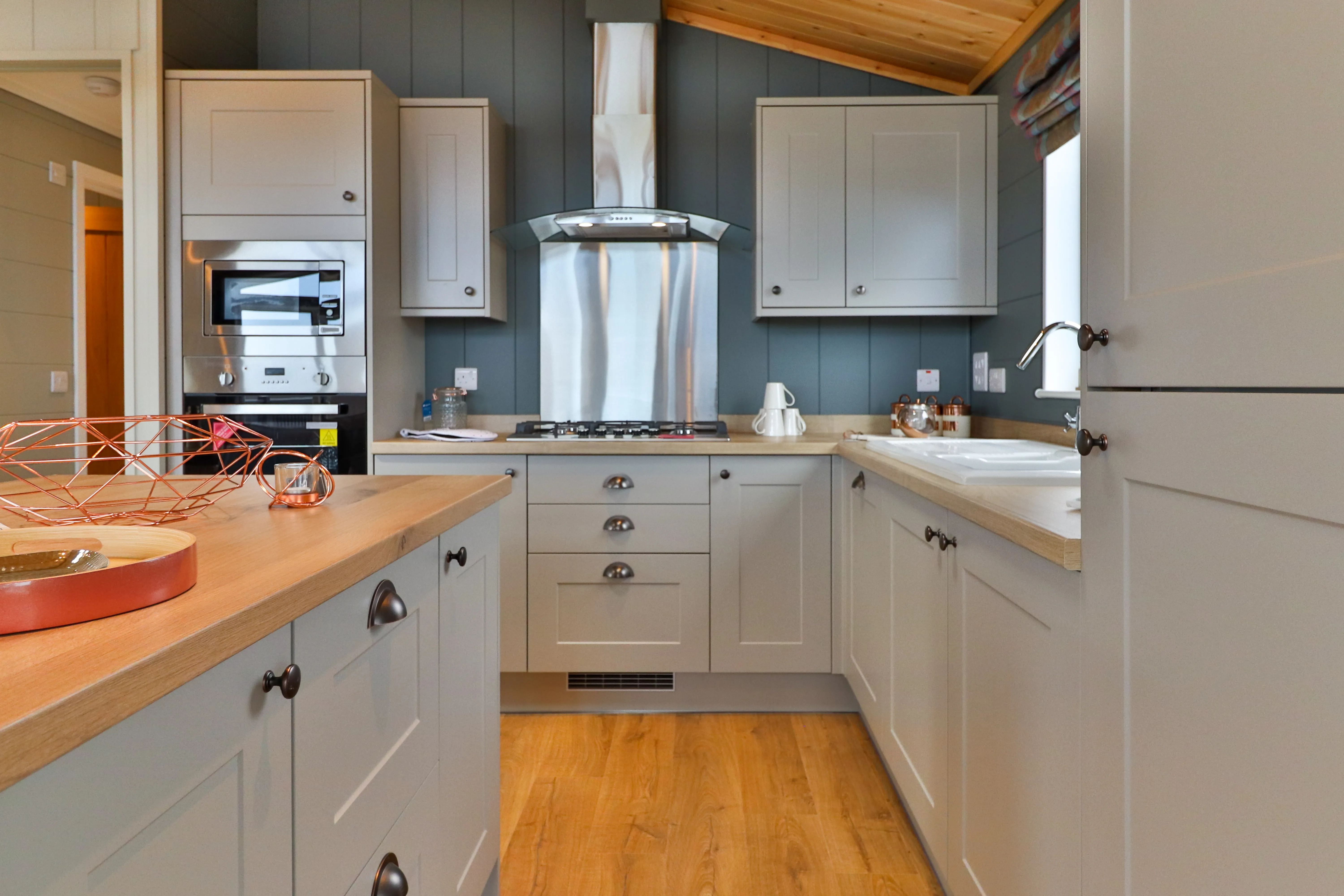 Modern kitchen with grey cabinets, wooden worktops, and stainless steel cooker hood