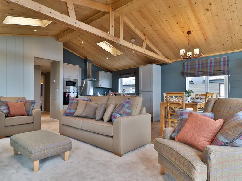 Cosy open-plan living room and kitchen with wooden vaulted ceiling, sofas and dining table