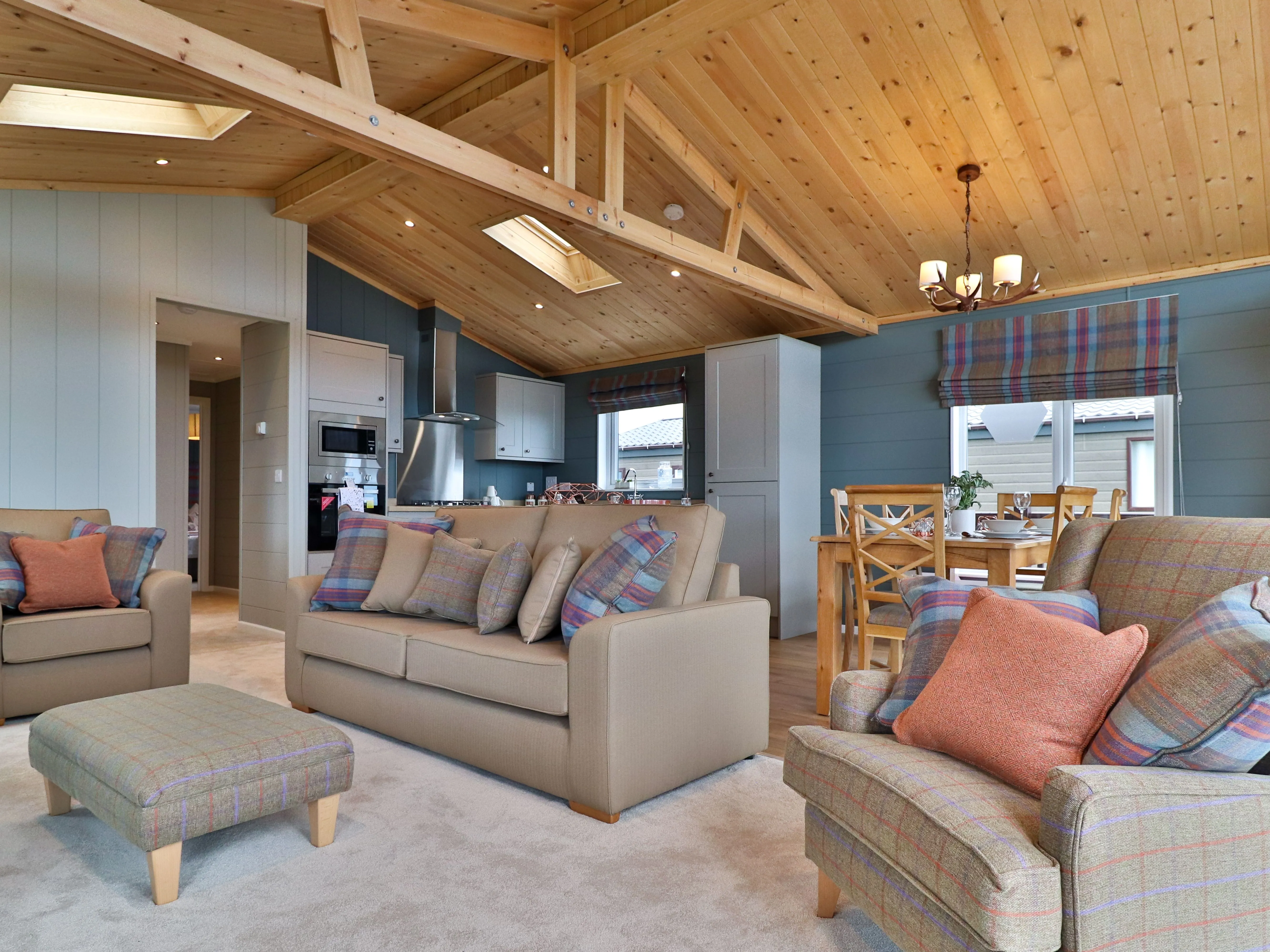 Cosy open-plan living room and kitchen with wooden vaulted ceiling, sofas and dining table