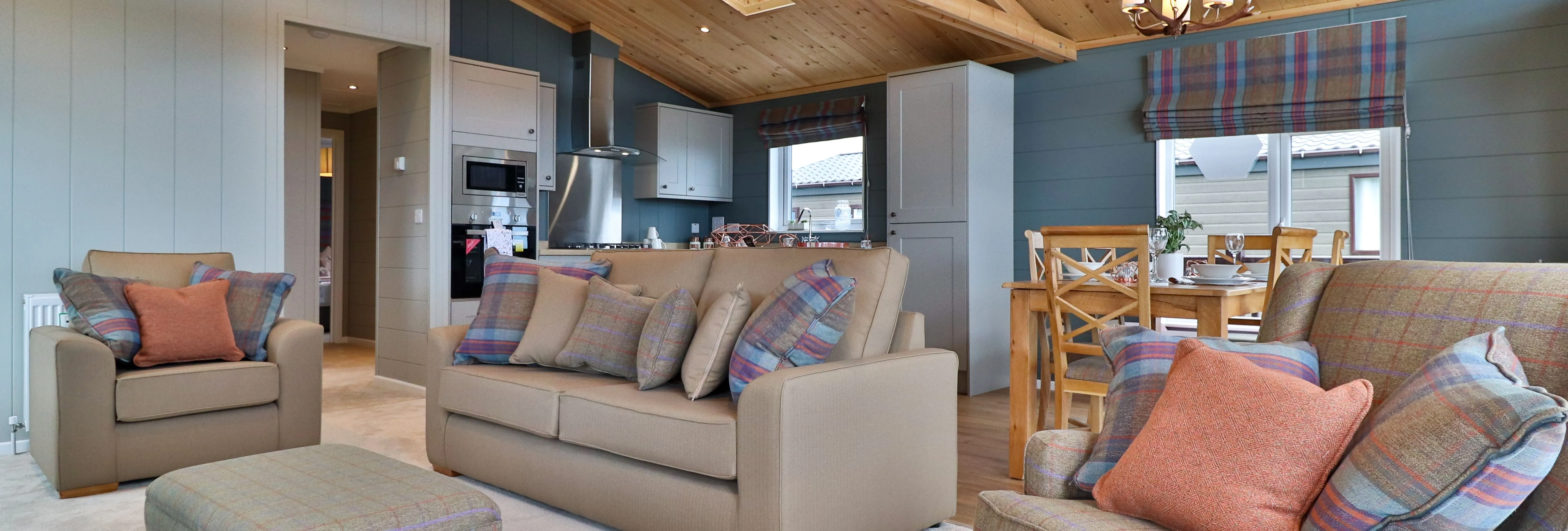 Cosy open-plan living room and kitchen with wooden vaulted ceiling, sofas and dining table