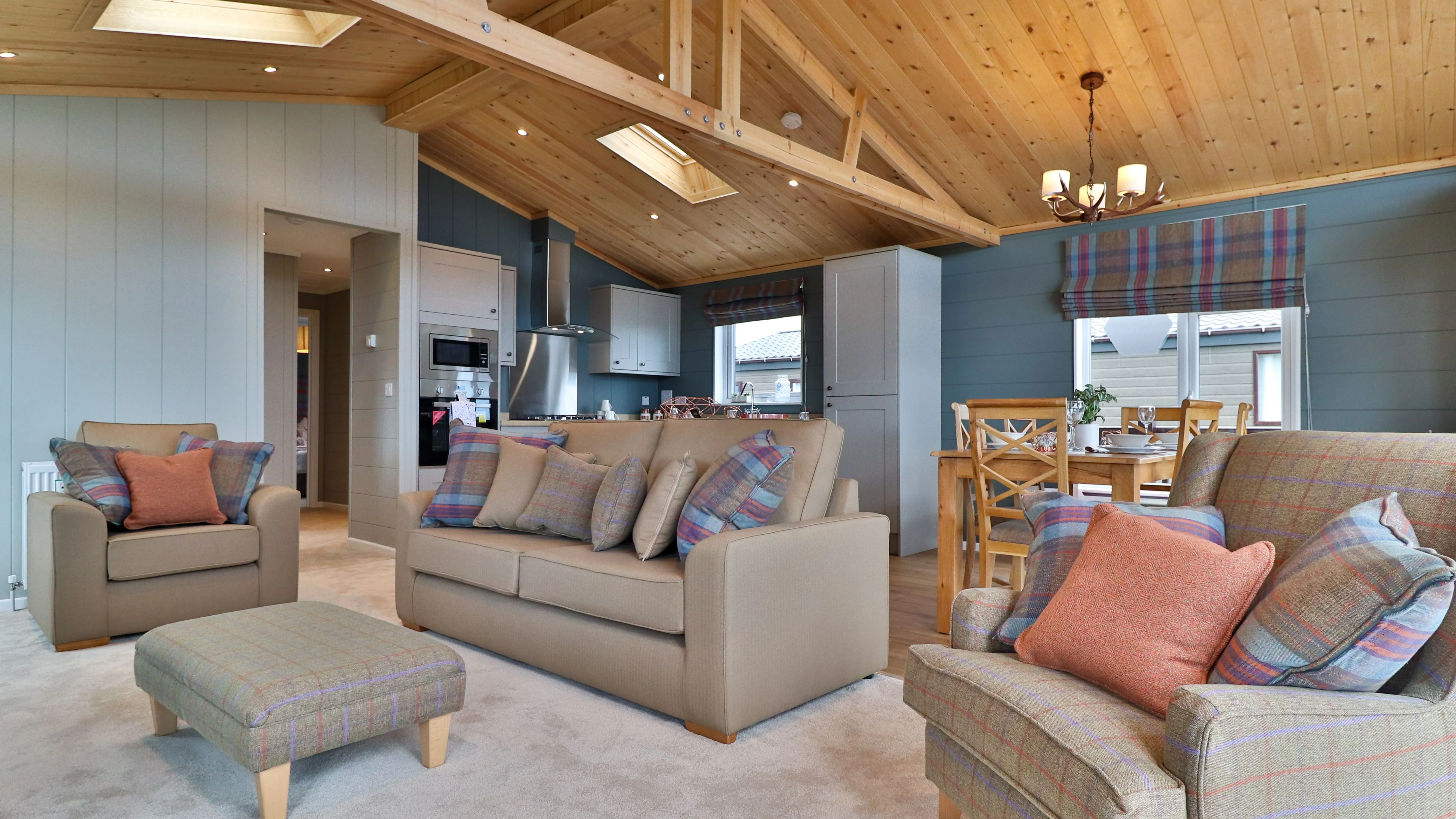 Cosy open-plan living room and kitchen with wooden vaulted ceiling, sofas and dining table