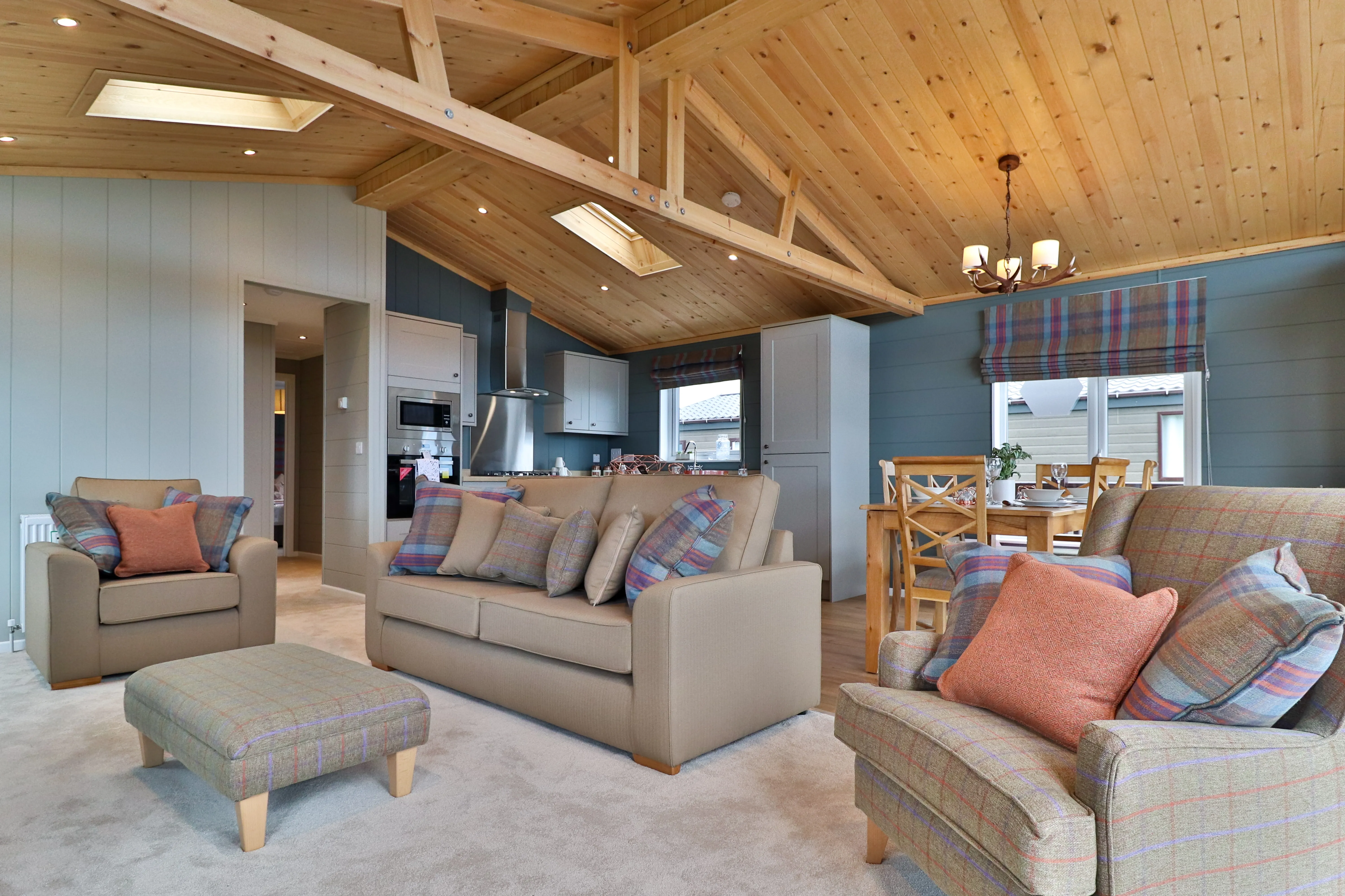 Cosy open-plan living room and kitchen with wooden vaulted ceiling, sofas and dining table