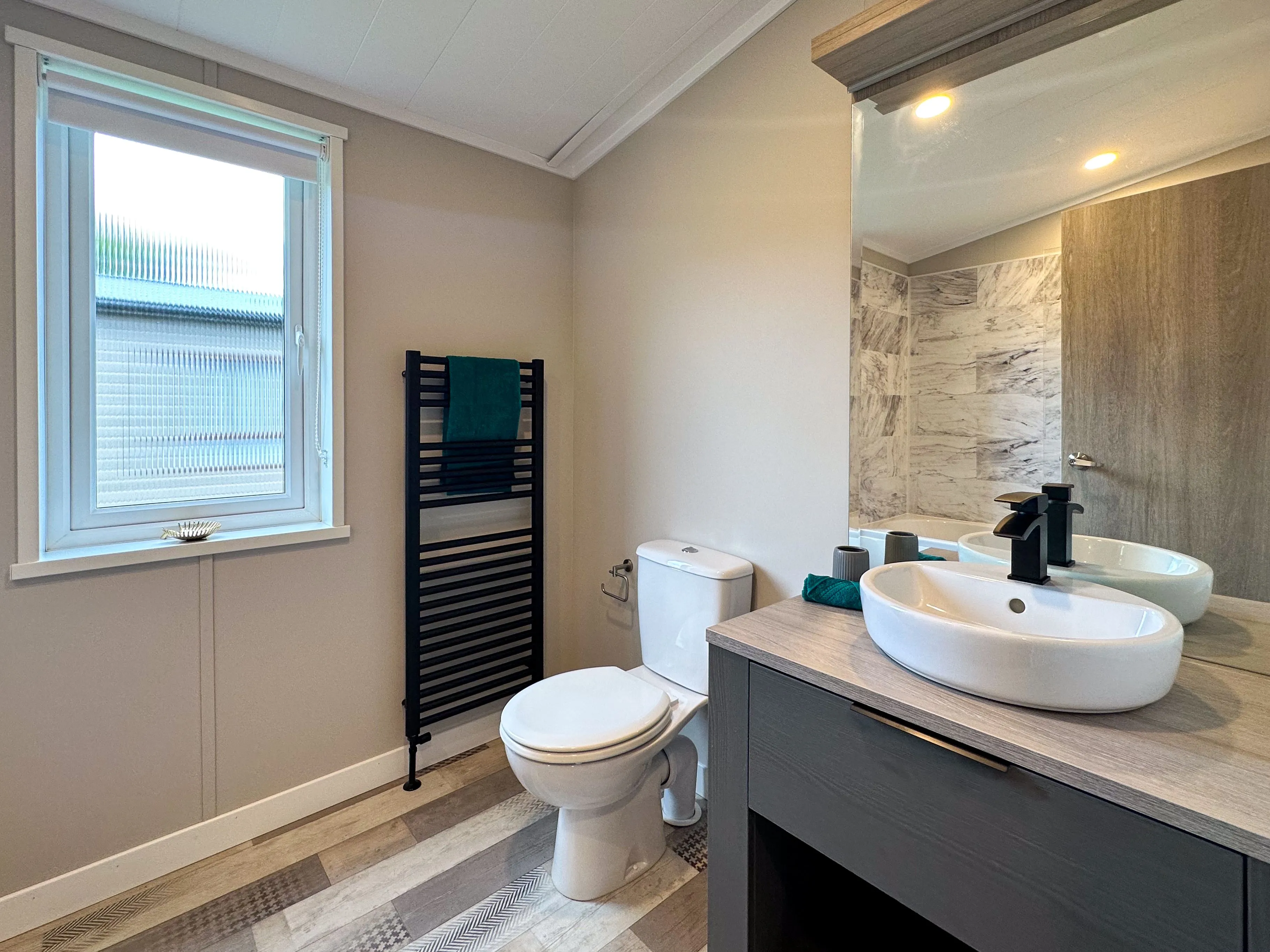 Modern bathroom with toilet, black heated towel rail, and vanity unit with vessel sink and mirror