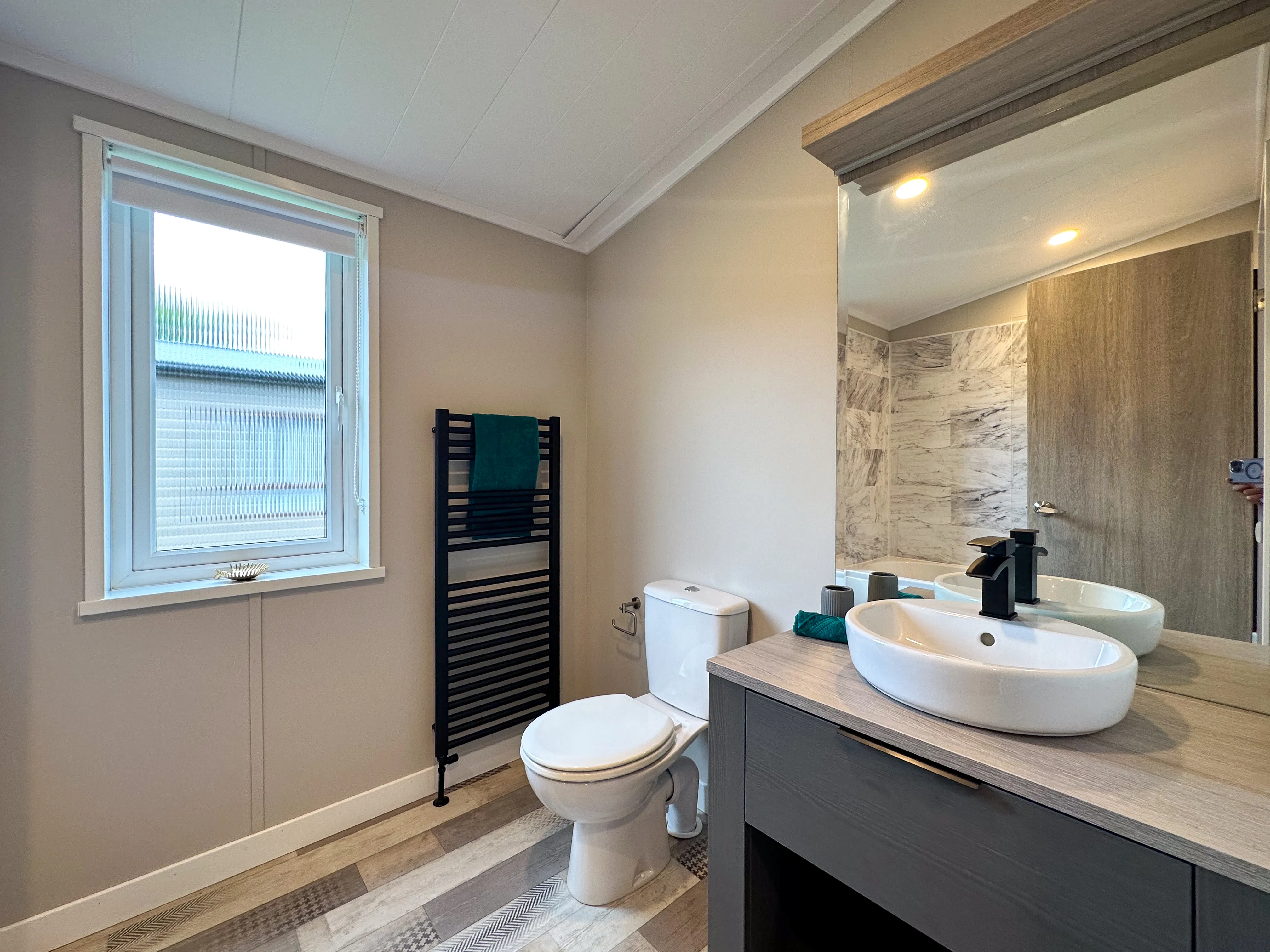 Modern bathroom with toilet, black heated towel rail, and vanity unit with vessel sink and mirror