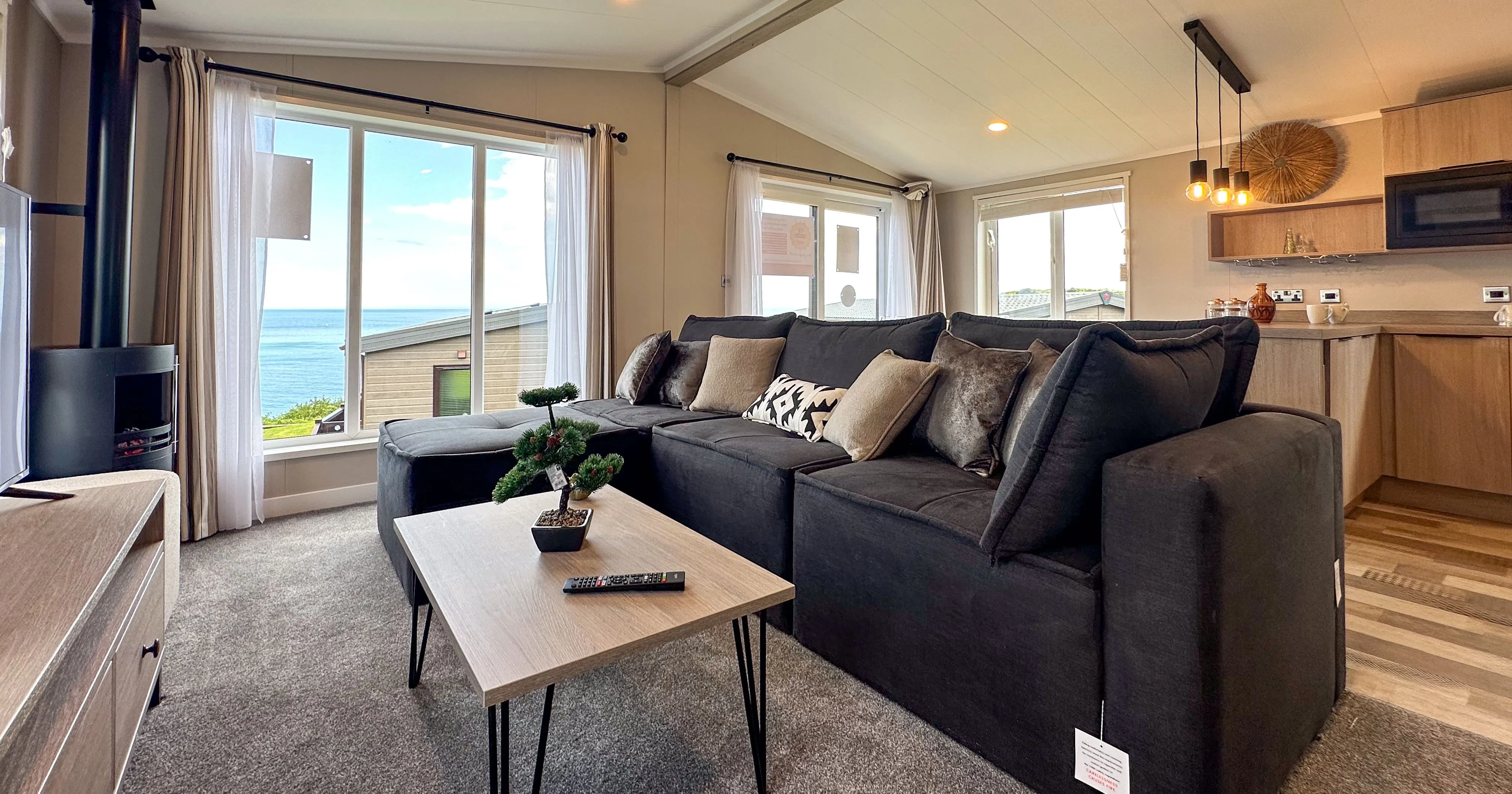 Modern open-plan living room with dark sectional sofa and large windows overlooking the sea