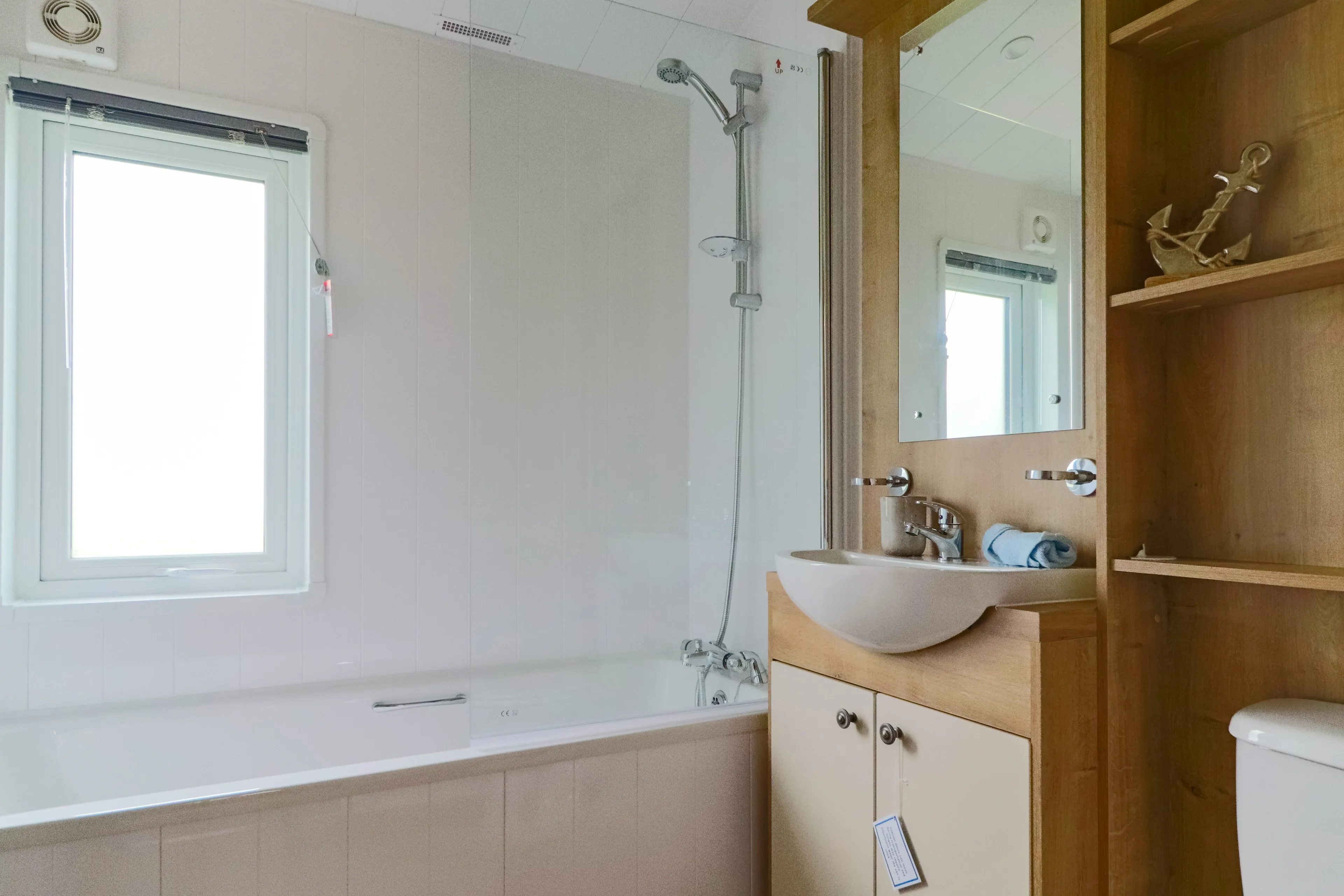 Bright bathroom with a bathtub, wall-mounted shower, sink vanity and window