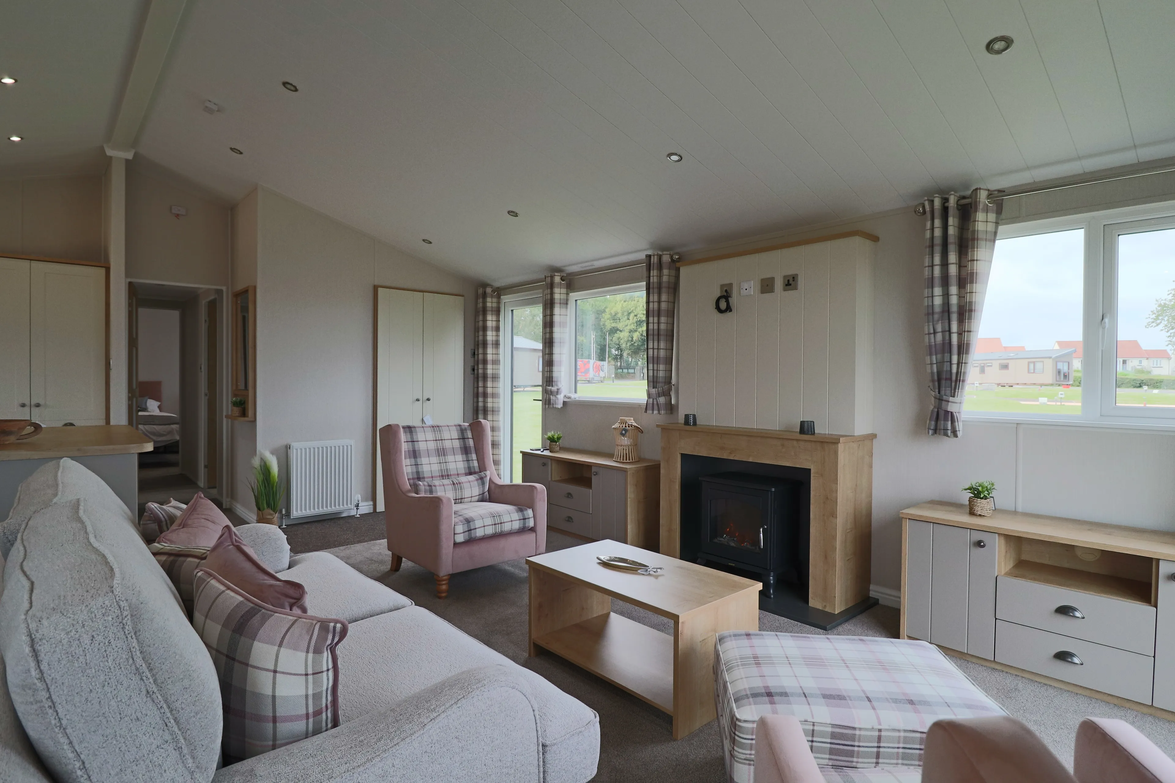 Cosy modern caravan lounge with sofa, armchair, fireplace and large windows