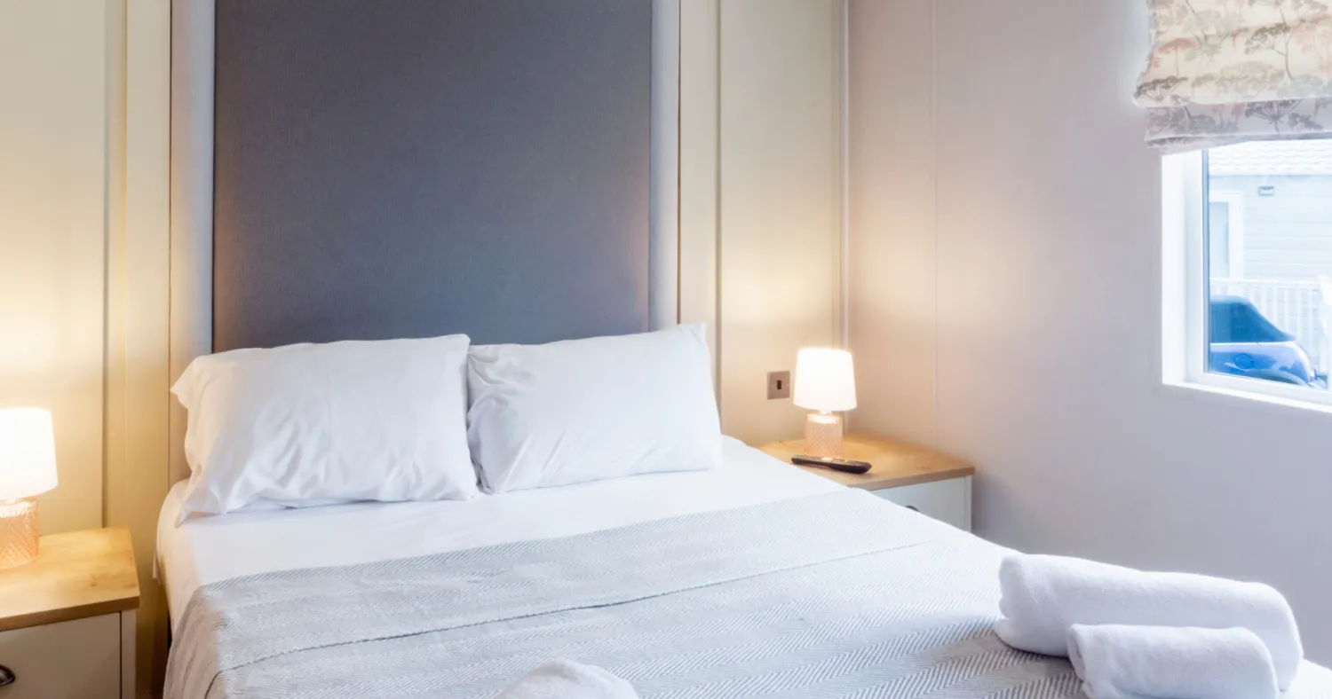 Neat bedroom with double bed, white bedding and bedside lamps