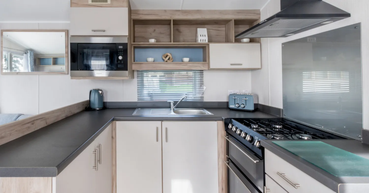 Modern compact kitchen with gas hob, extractor hood and corner sink