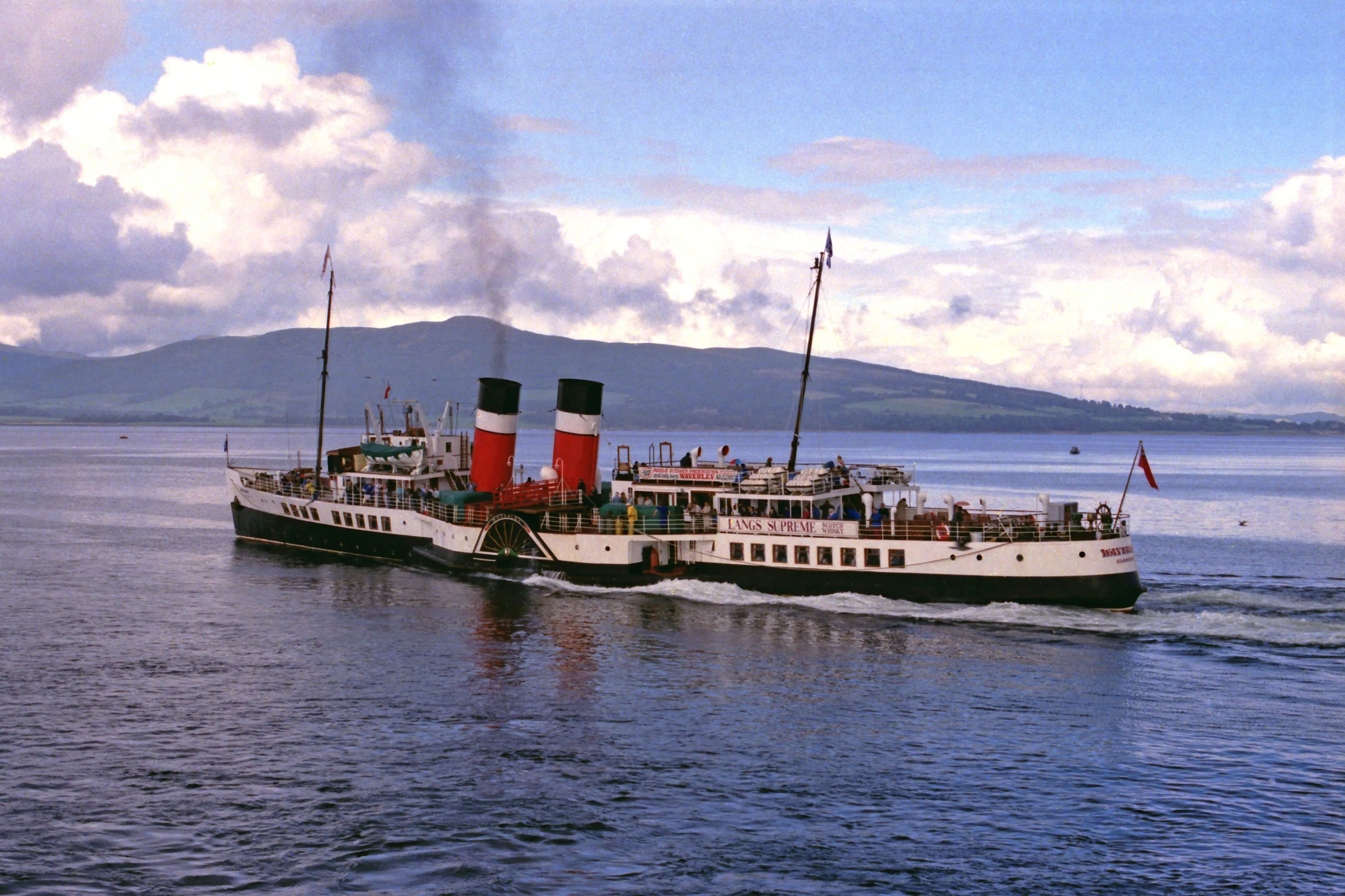 Vintage paddle steamer crossing a calm loch with mountains in the background