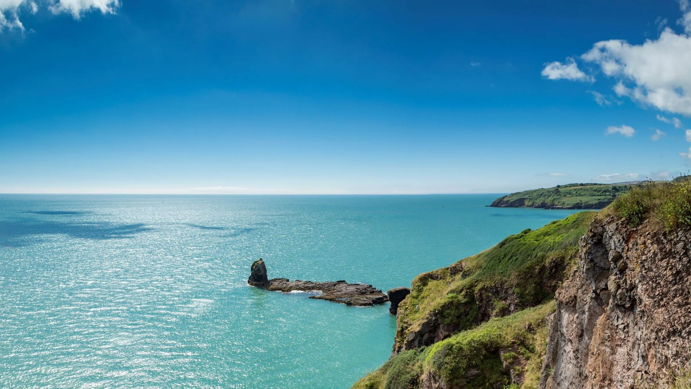 Coastal view near Landscove Holiday Park with rugged cliffs, turquoise sea and clear blue sky