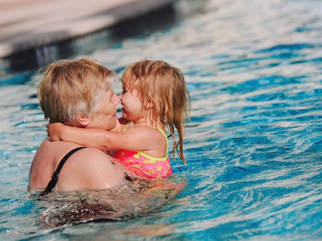 Older woman holding and cuddling a young girl in a swimming pool