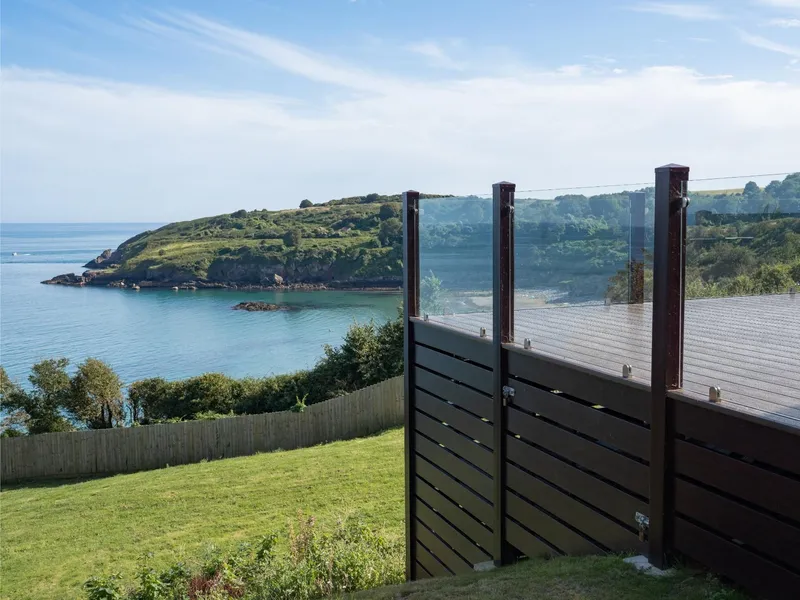 Cliff-top lodge decking with glass balustrade overlooking sea views at Riviera Bay, Devon