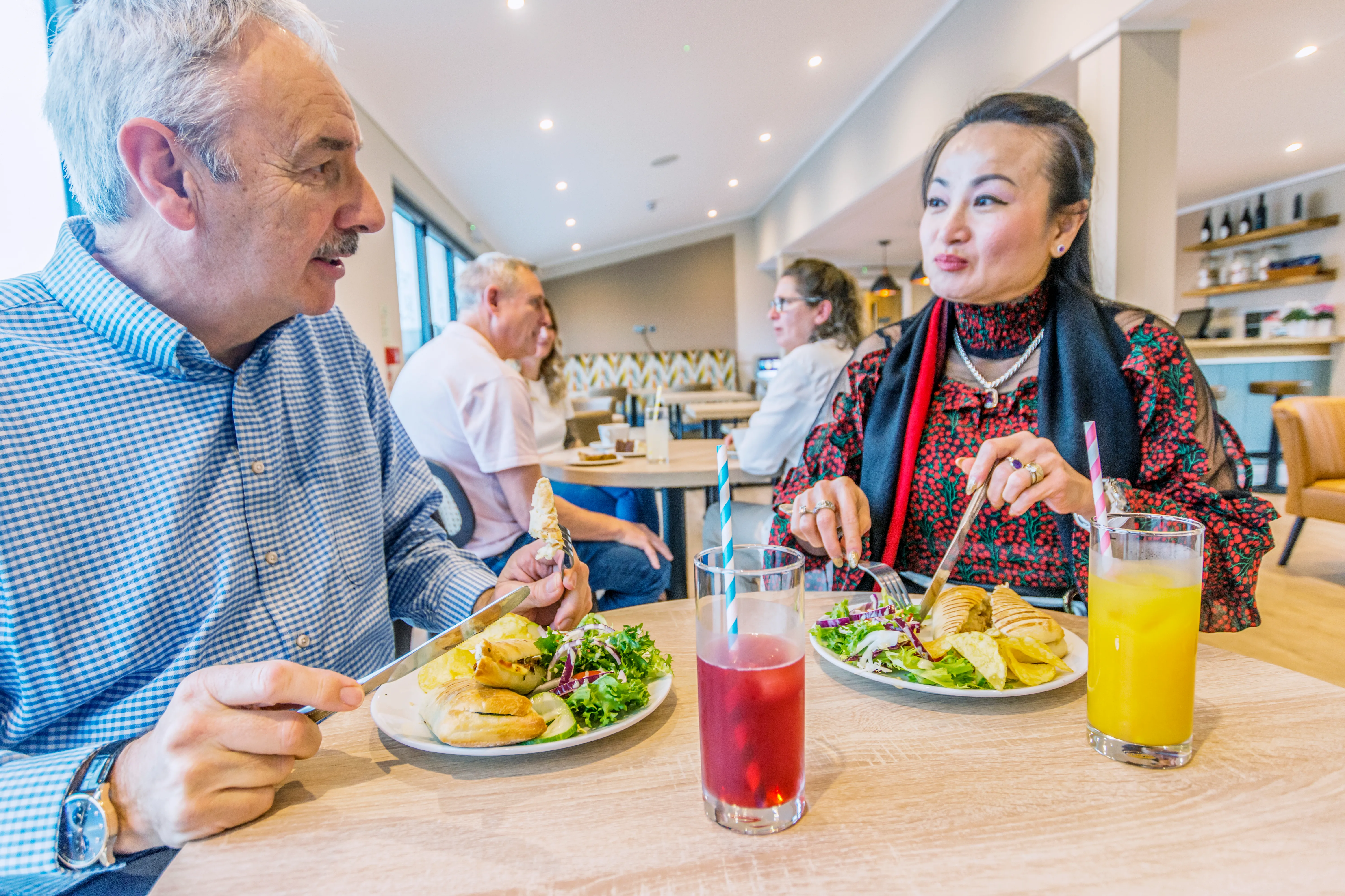 Two people enjoying lunch and drinks together in a bright café restaurant.