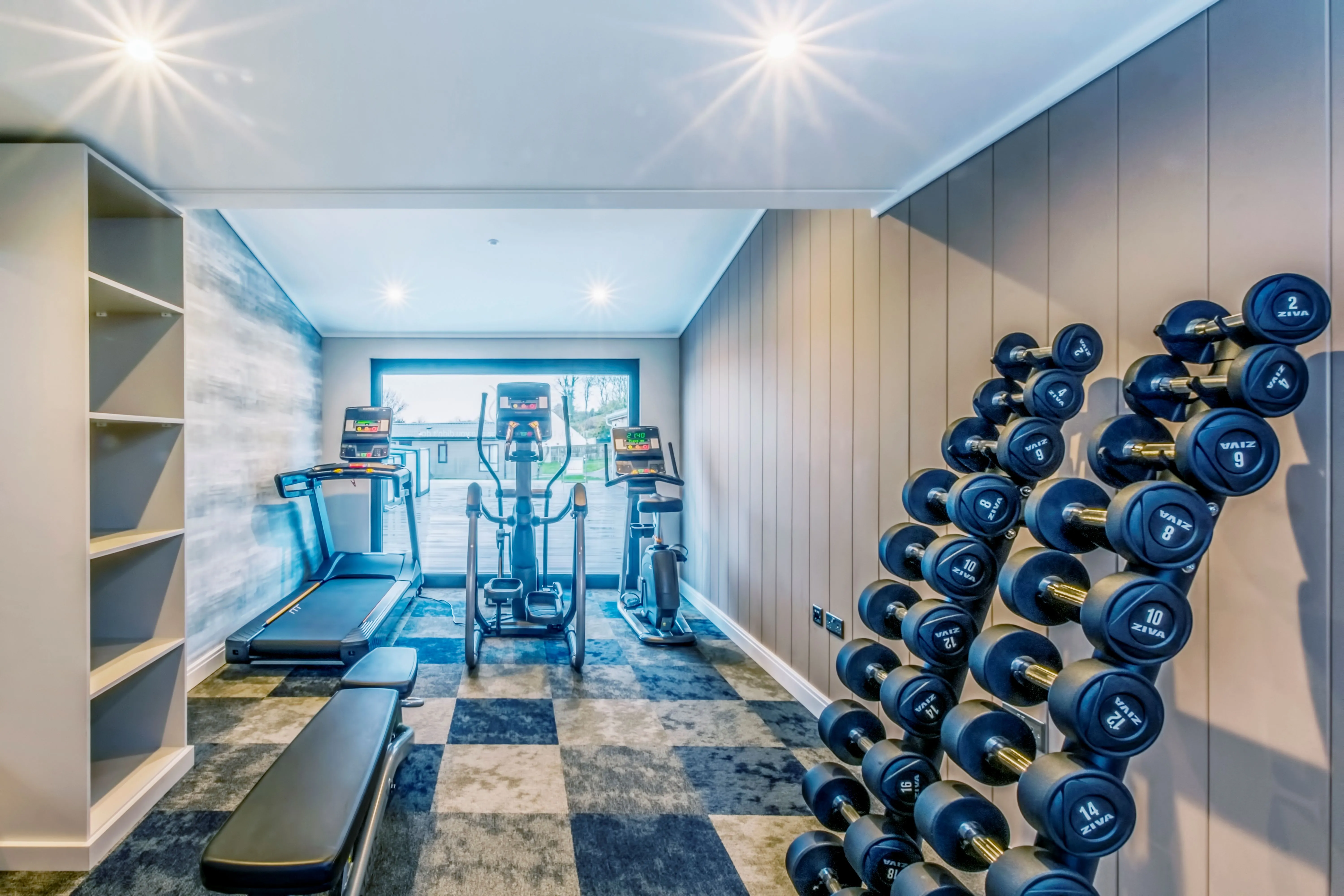 Modern home gym with treadmill, cross trainer, exercise bike and dumbbell rack