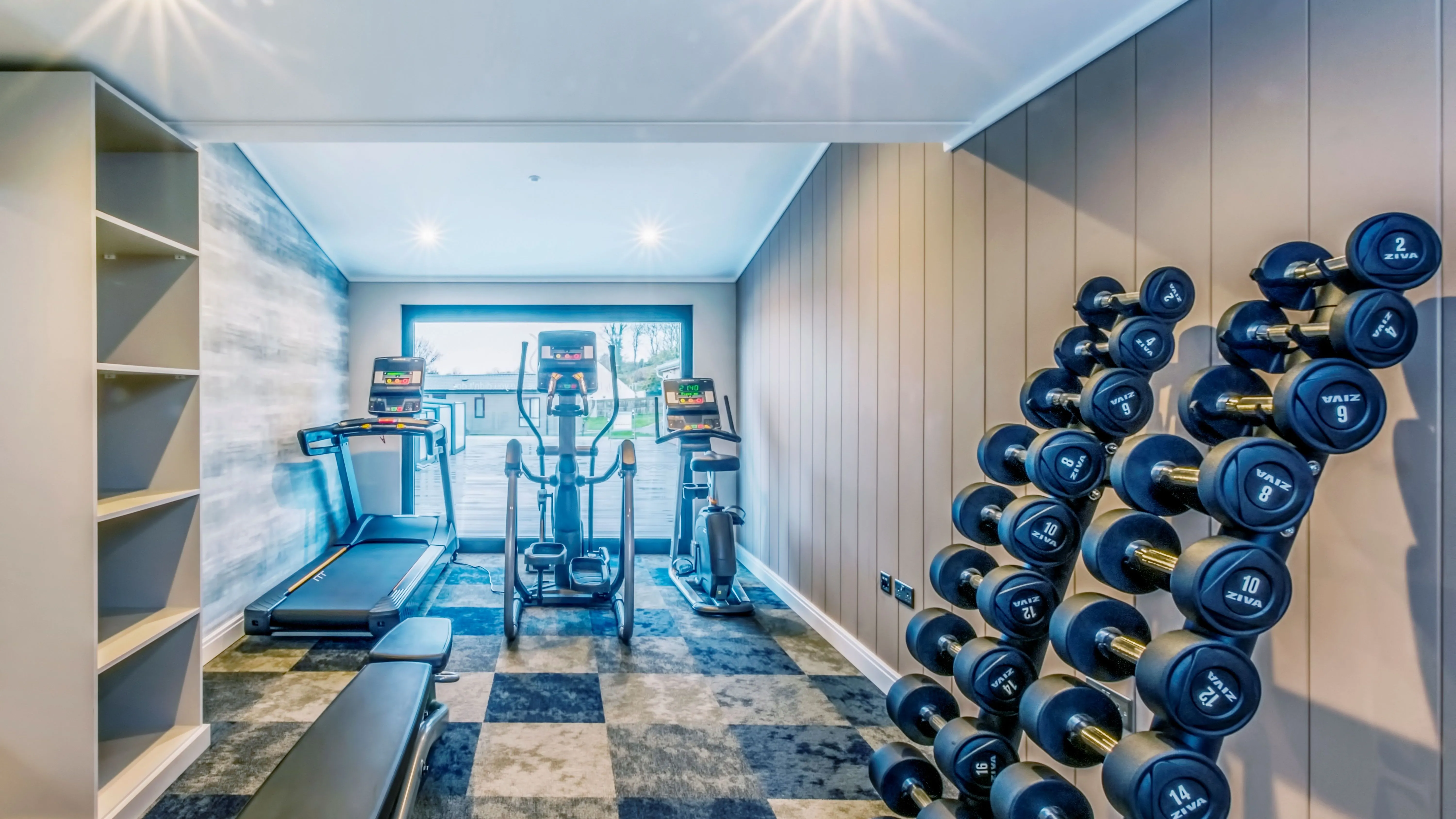 Modern home gym with treadmill, cross trainer, exercise bike and dumbbell rack