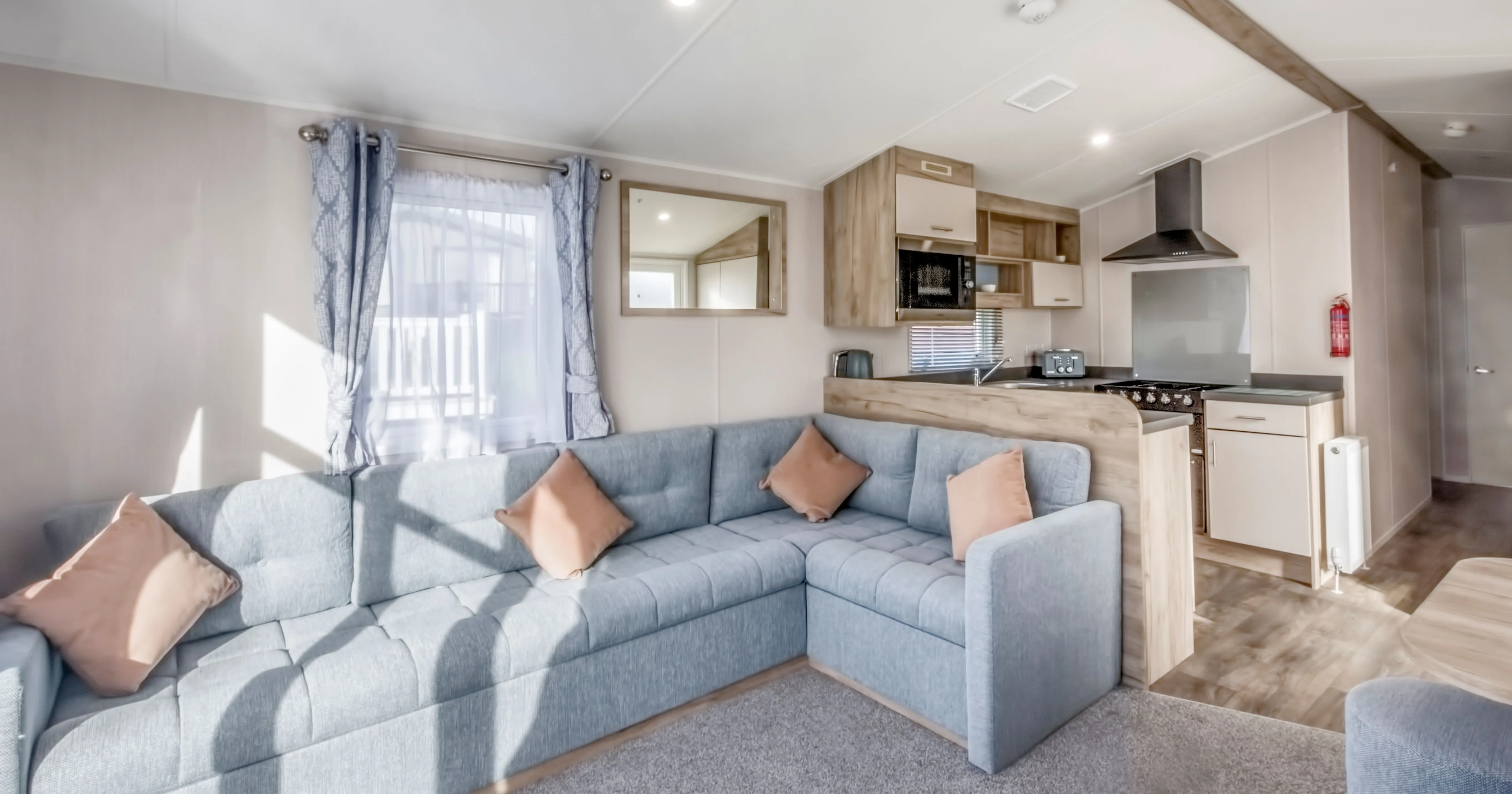 Bright modern caravan lounge with a grey corner sofa, dining area and open-plan kitchen