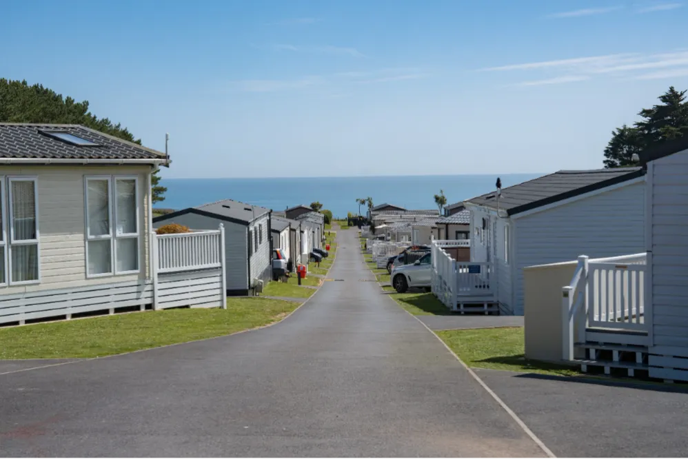 Road through a coastal holiday park with static caravans leading to the sea