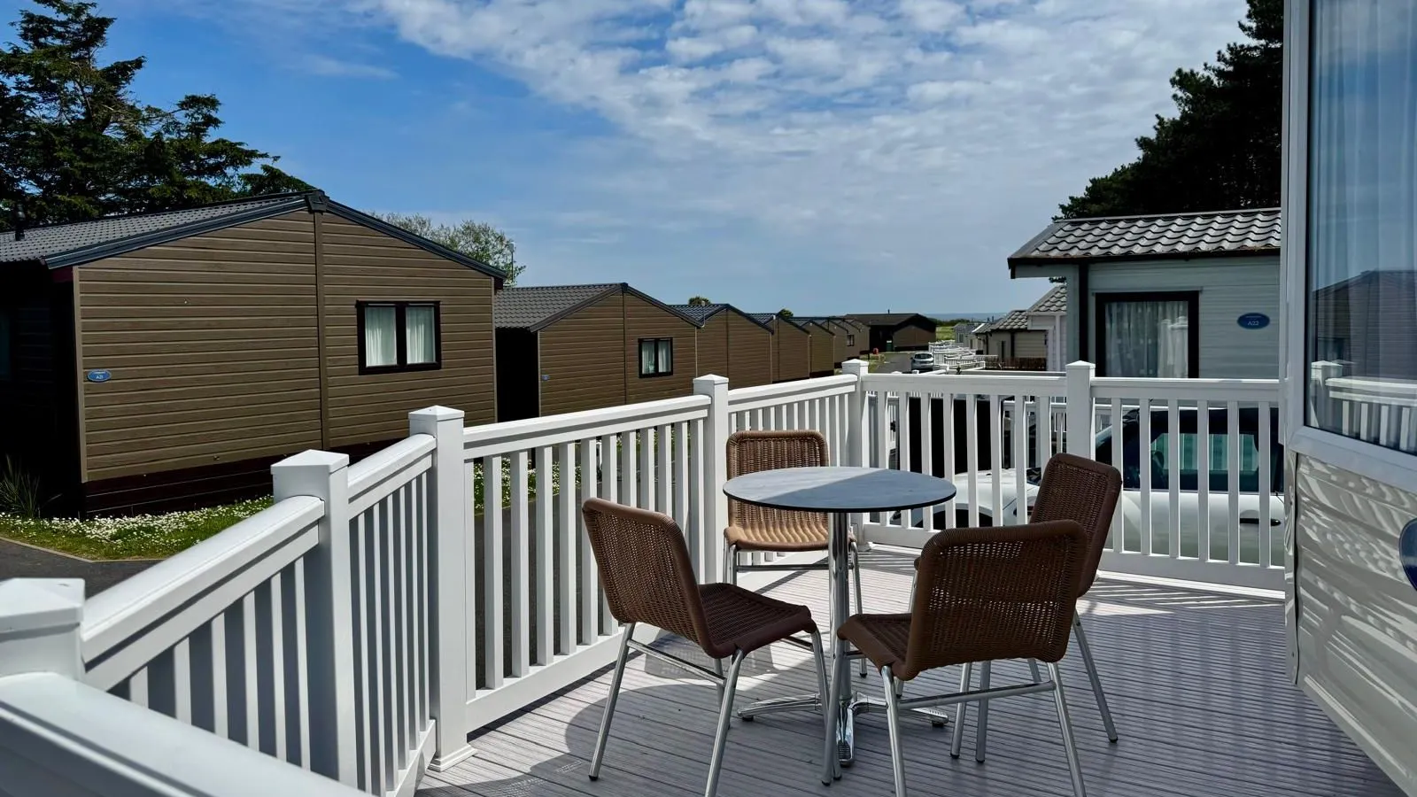 Private decking area with outdoor table and chairs at a modern holiday lodge
